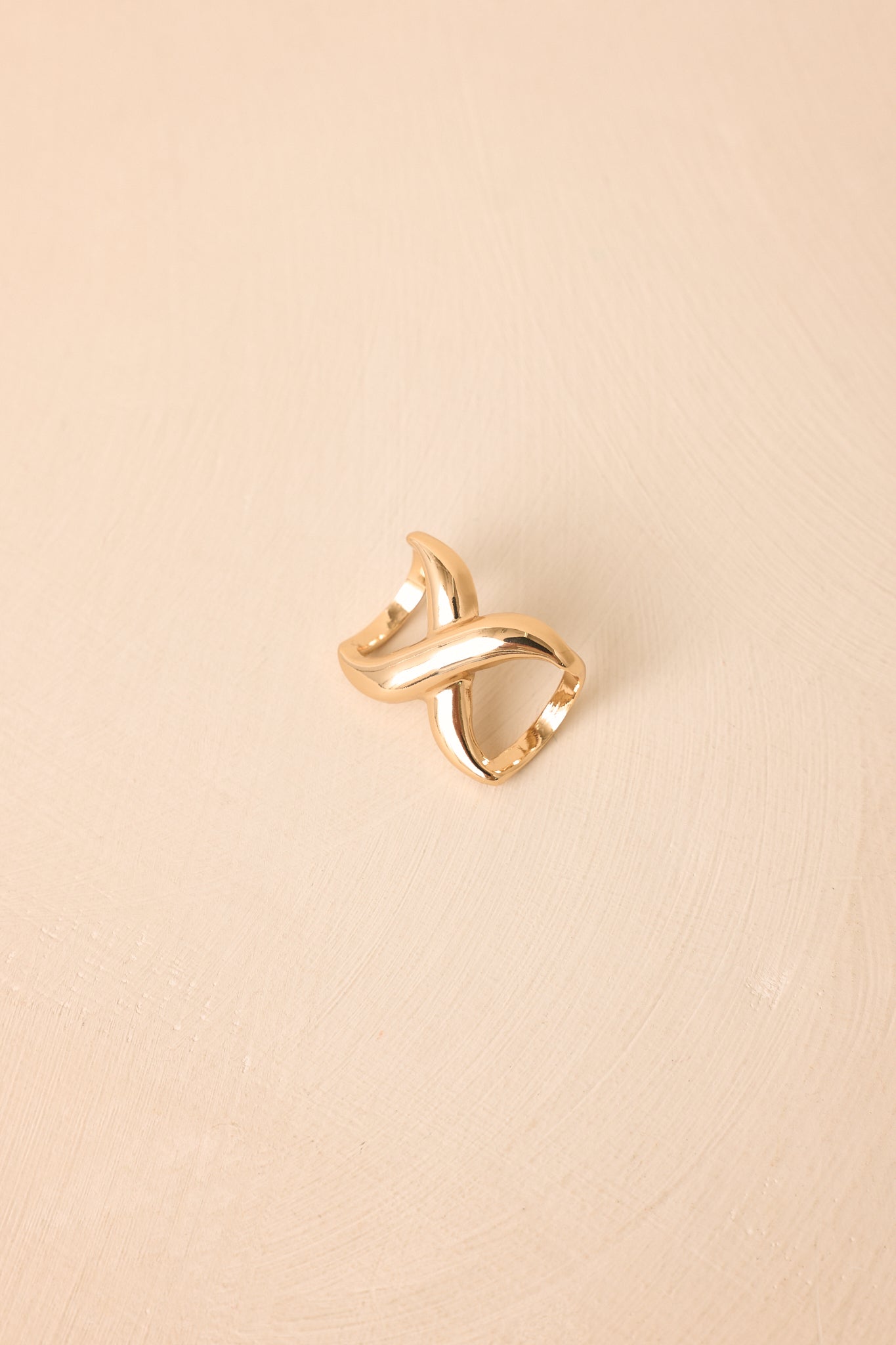 Close-up of the gold-tone scarf ring showcasing the smooth crisscross silhouette, polished finish, and refined craftsmanship.