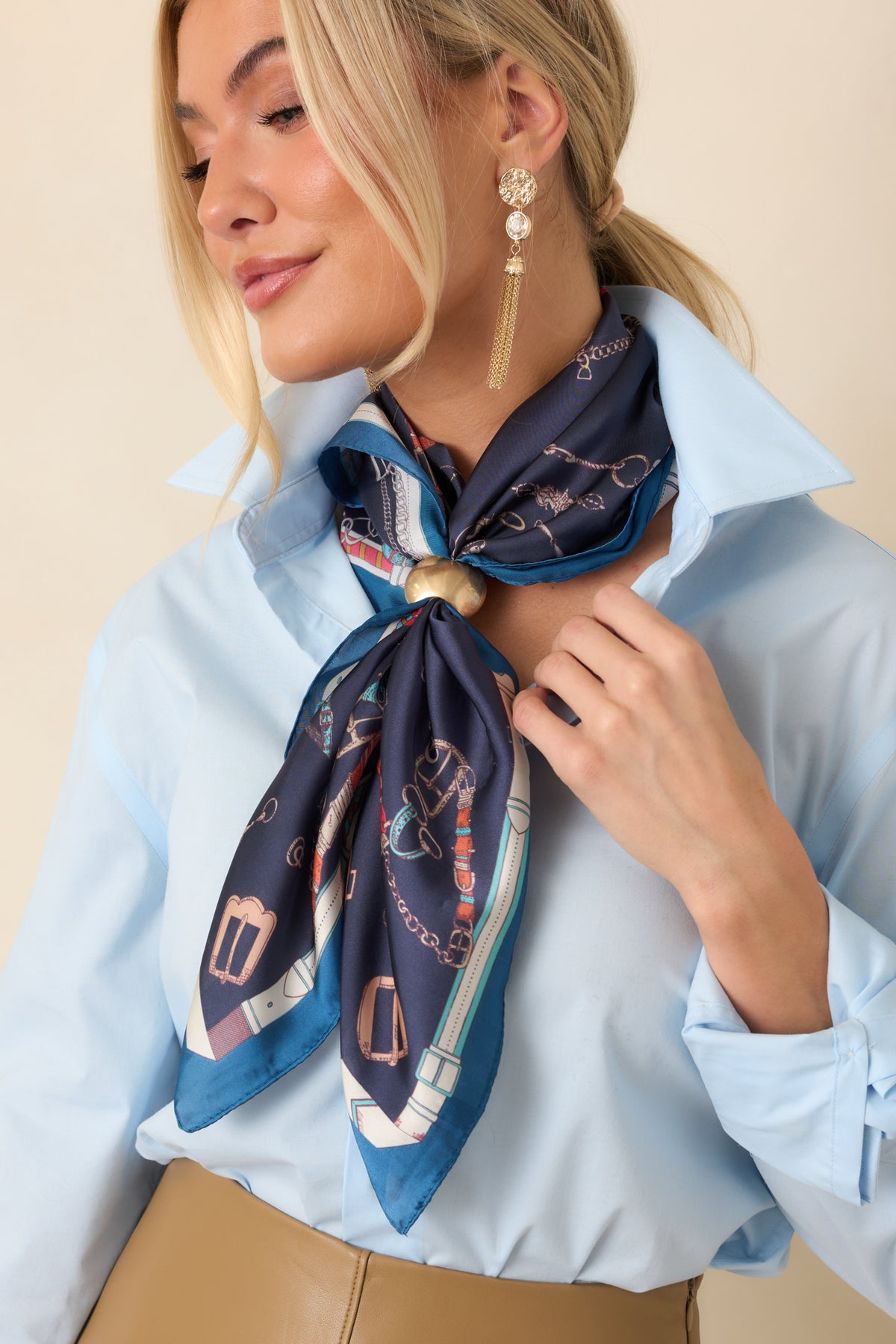 Gold-tone scarf accessory featuring a sculptural silhouette, rounded edges, and a reflective metallic finish.
