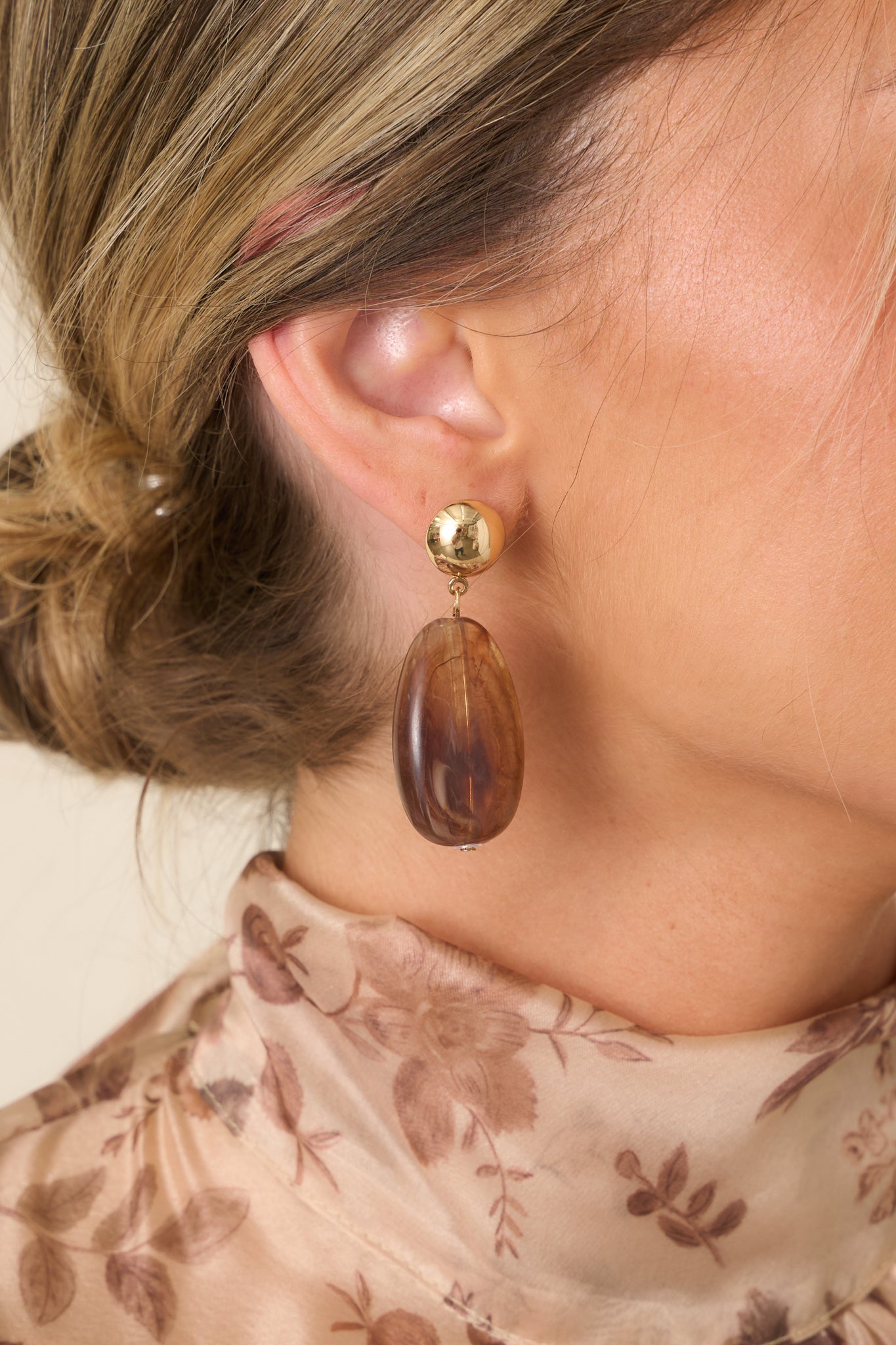 Closer look at the gold-tone stud earrings showcasing the contrast between the polished metal top and warm marbled tortoise bead.