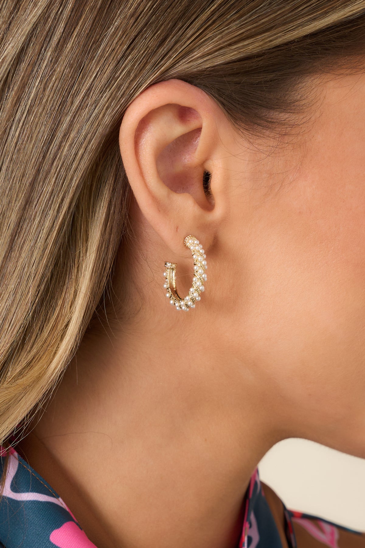 Gold-tone hoop earrings with a twisting silhouette and clusters of luminous faux pearls in varying sizes.