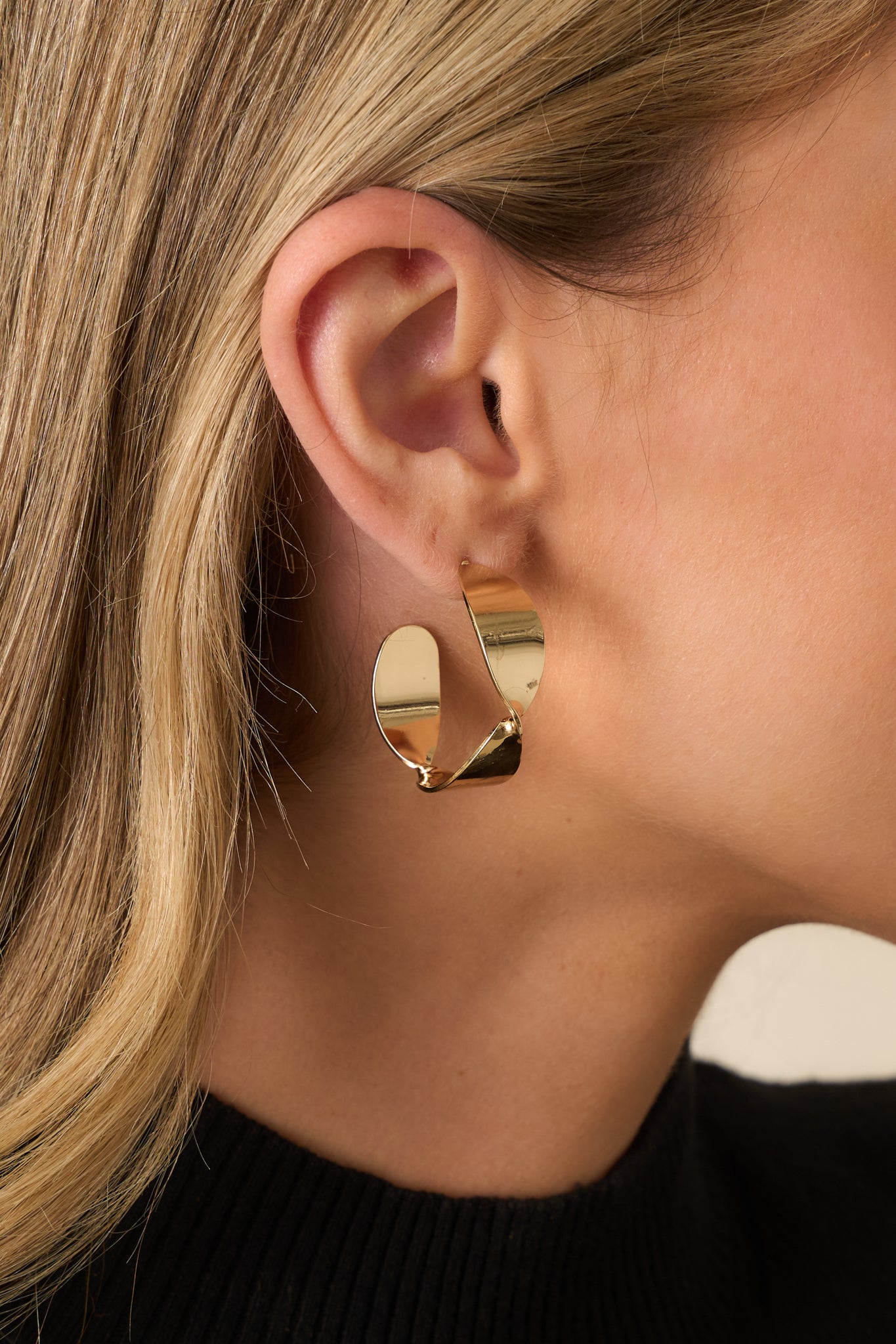 A close-up of one earring showing the detailed twisted gold texture and secure post back.