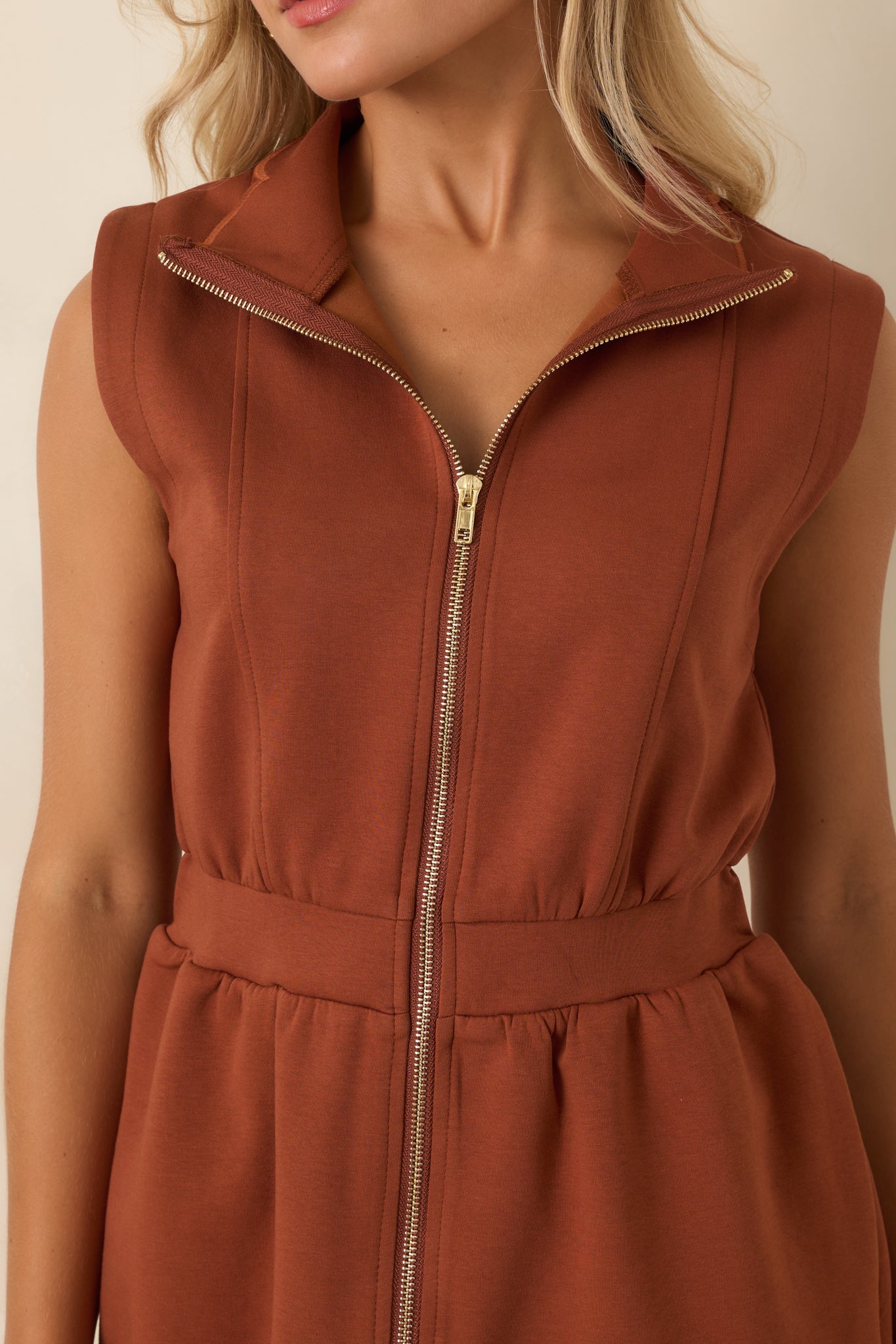 Detailed view of the gold front zipper, stand collar, structured fabric, and scalloped hem finishing on the mini dress.