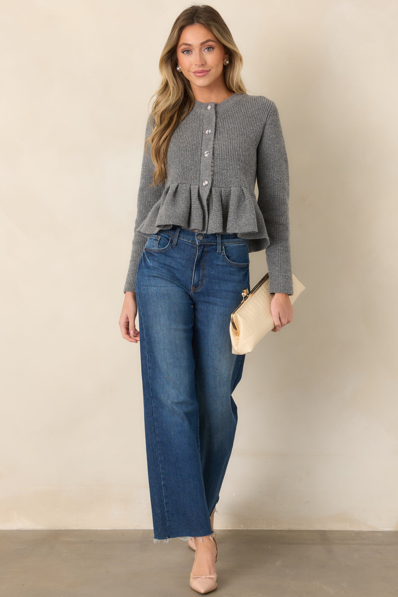 Soft gray knit cardigan with a fitted silhouette that flares into a structured peplum hem, accented by plaid-covered buttons and matching trim.
