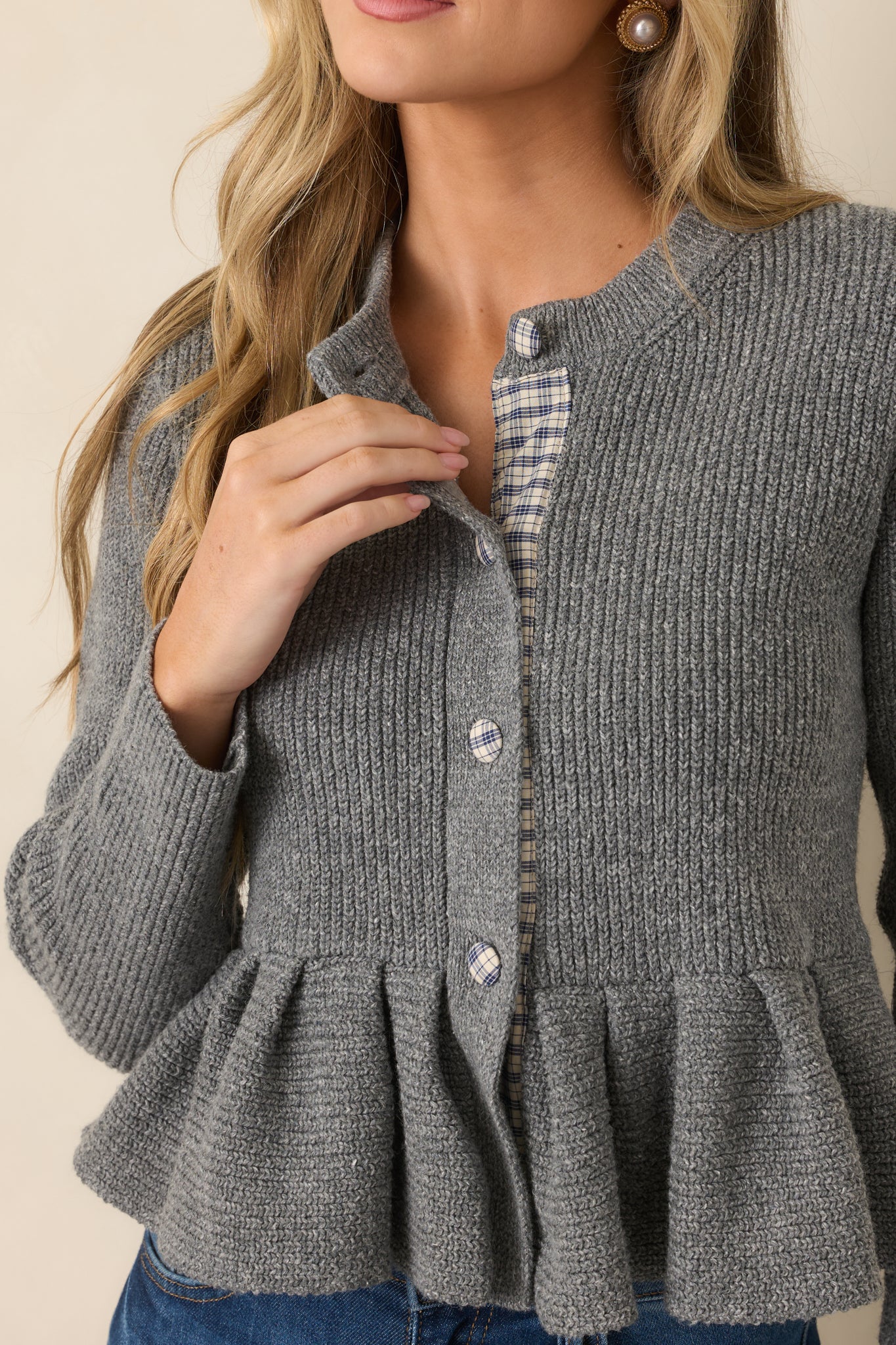 Close-up detail of the heather gray cardigan highlighting the plaid-covered buttons, contrasting plaid trim, and soft textured knit construction.