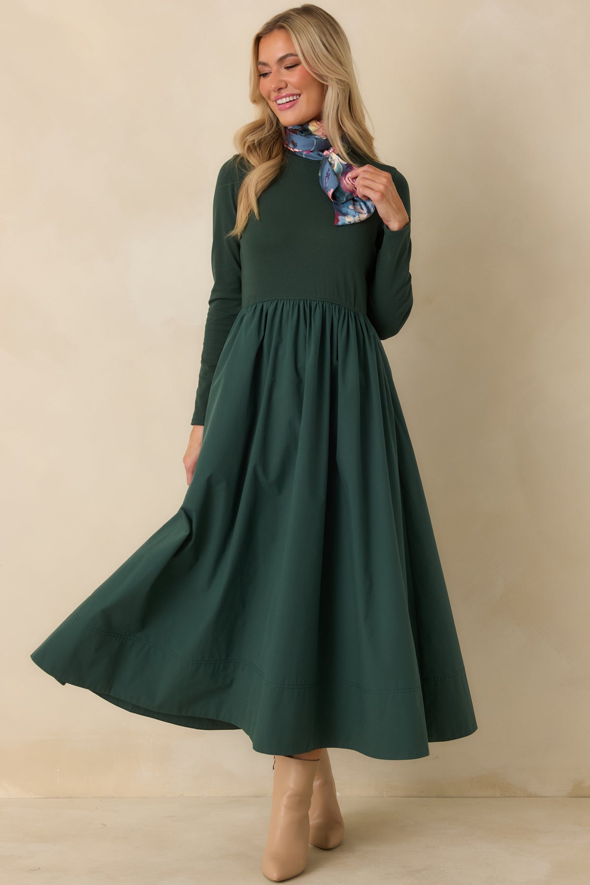 Green A-line midi dress with a soft knit bodice, classic round neckline, long sleeves, and a full skirt shown in movement.