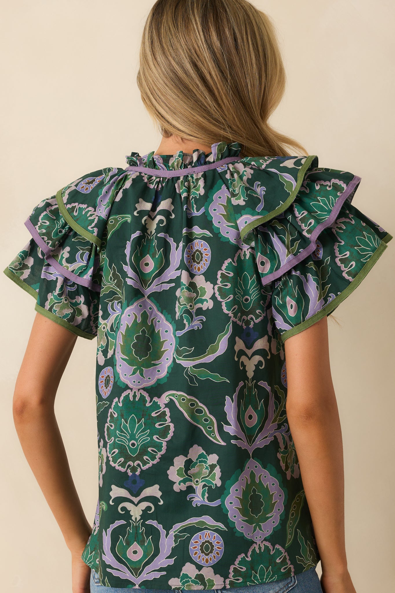 Rear view of green blouse showing relaxed fit, short ruffle sleeves, and multicolor print across the back.