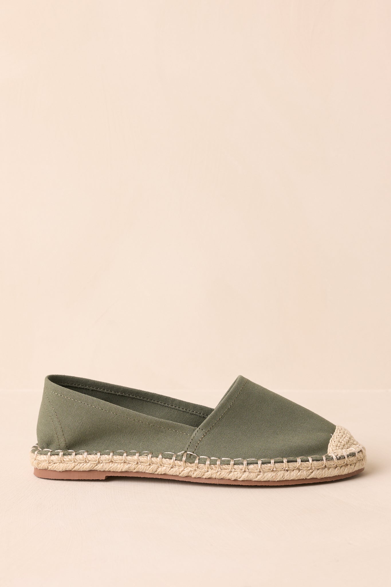 Another side view of green canvas flats showing the round closed-toe design and intricate crochet toe detail.