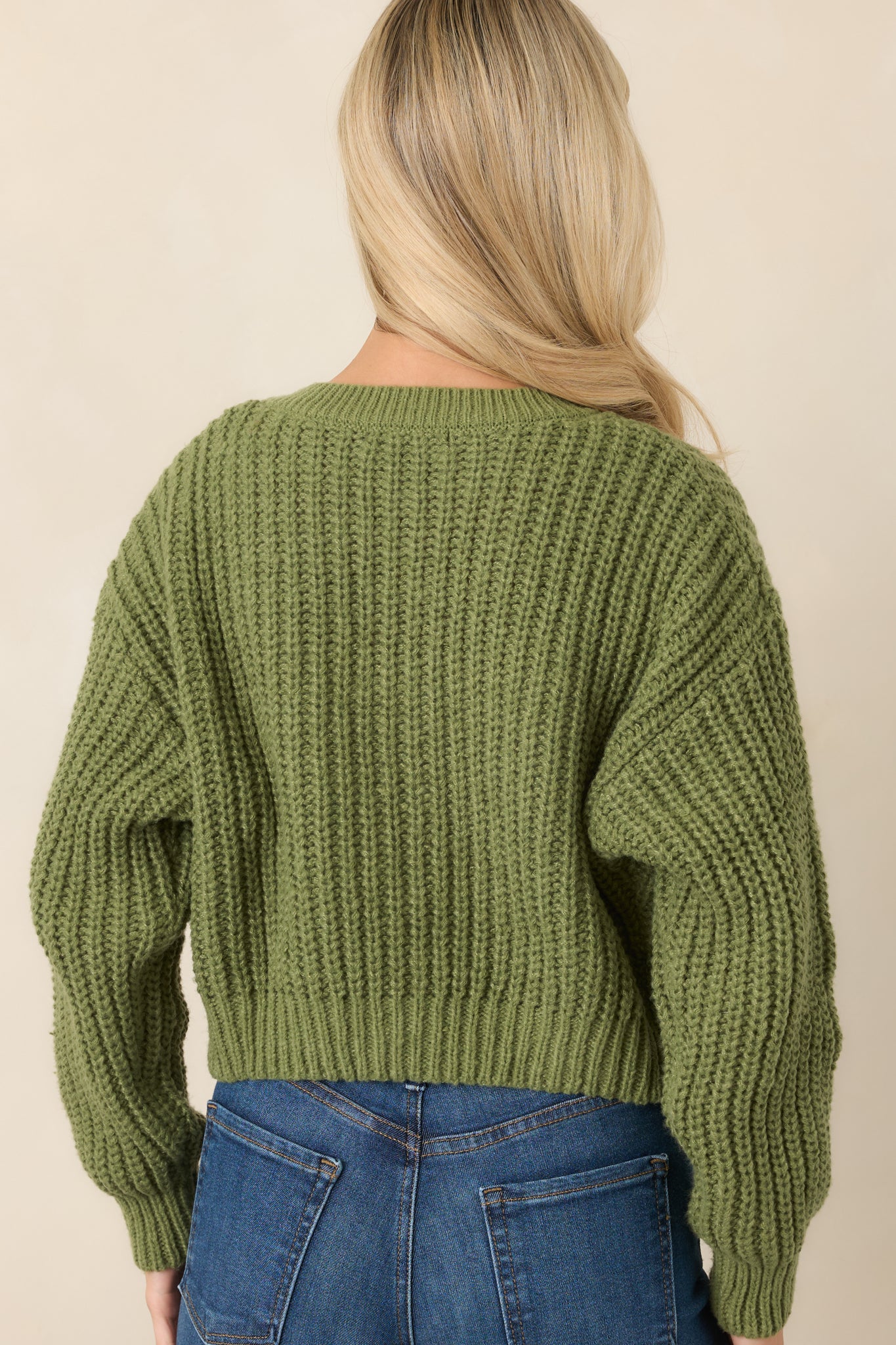 Rear view of the cropped green cardigan showcasing the chunky cable-inspired knit texture, long sleeves, and ribbed hem.