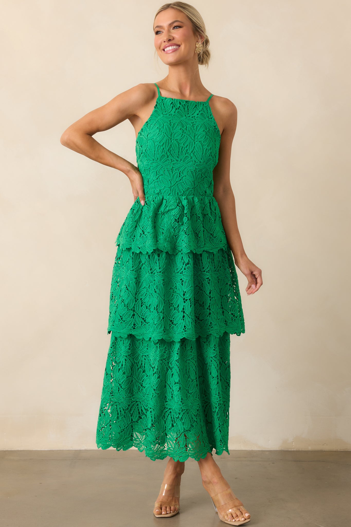 Front-facing green dress with apron neckline and visible green lining beneath an abstract embroidered overlay.