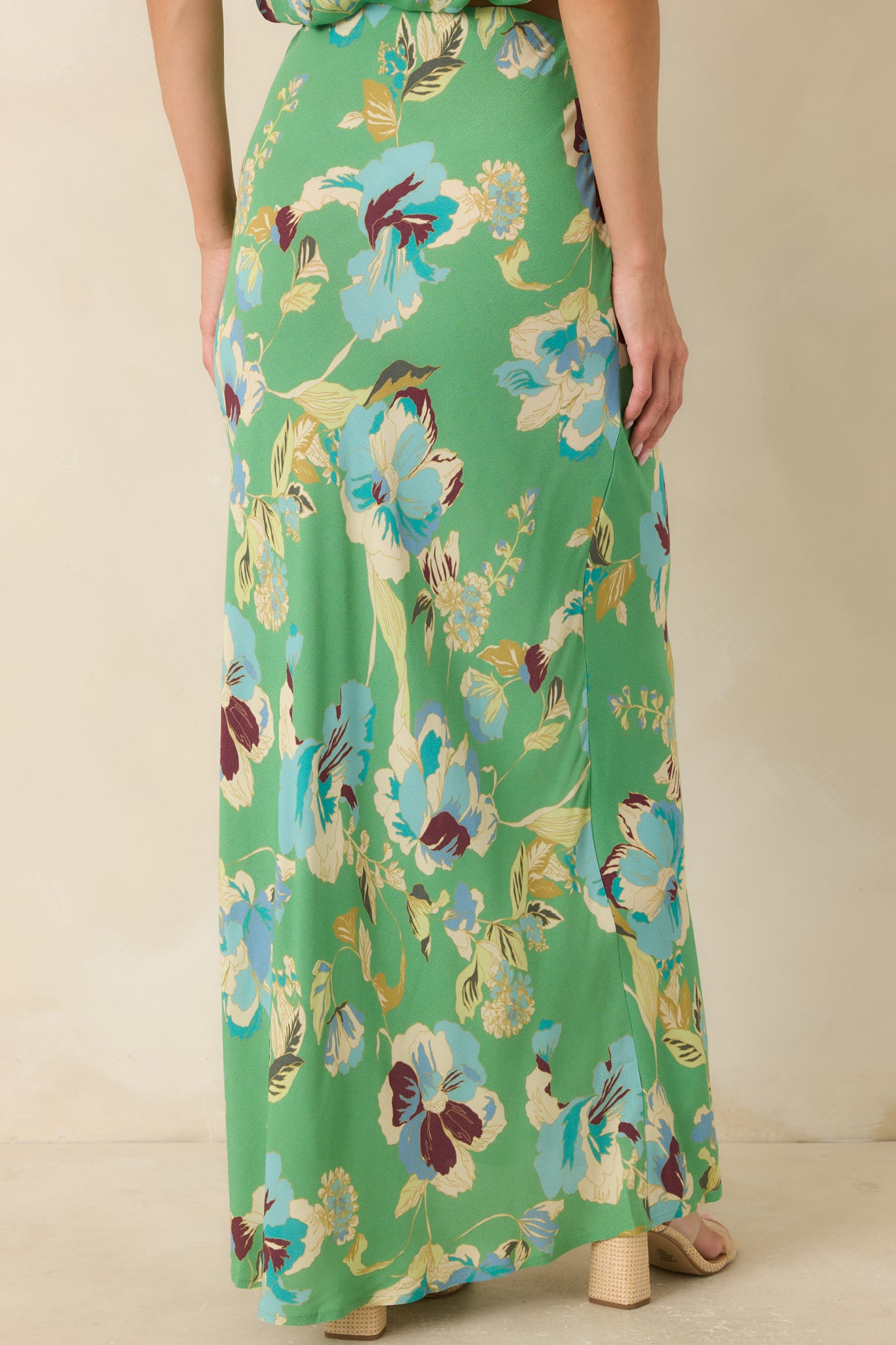 Back of the green floral maxi skirt featuring a smooth elastic waistband and flowing bias-cut silhouette.