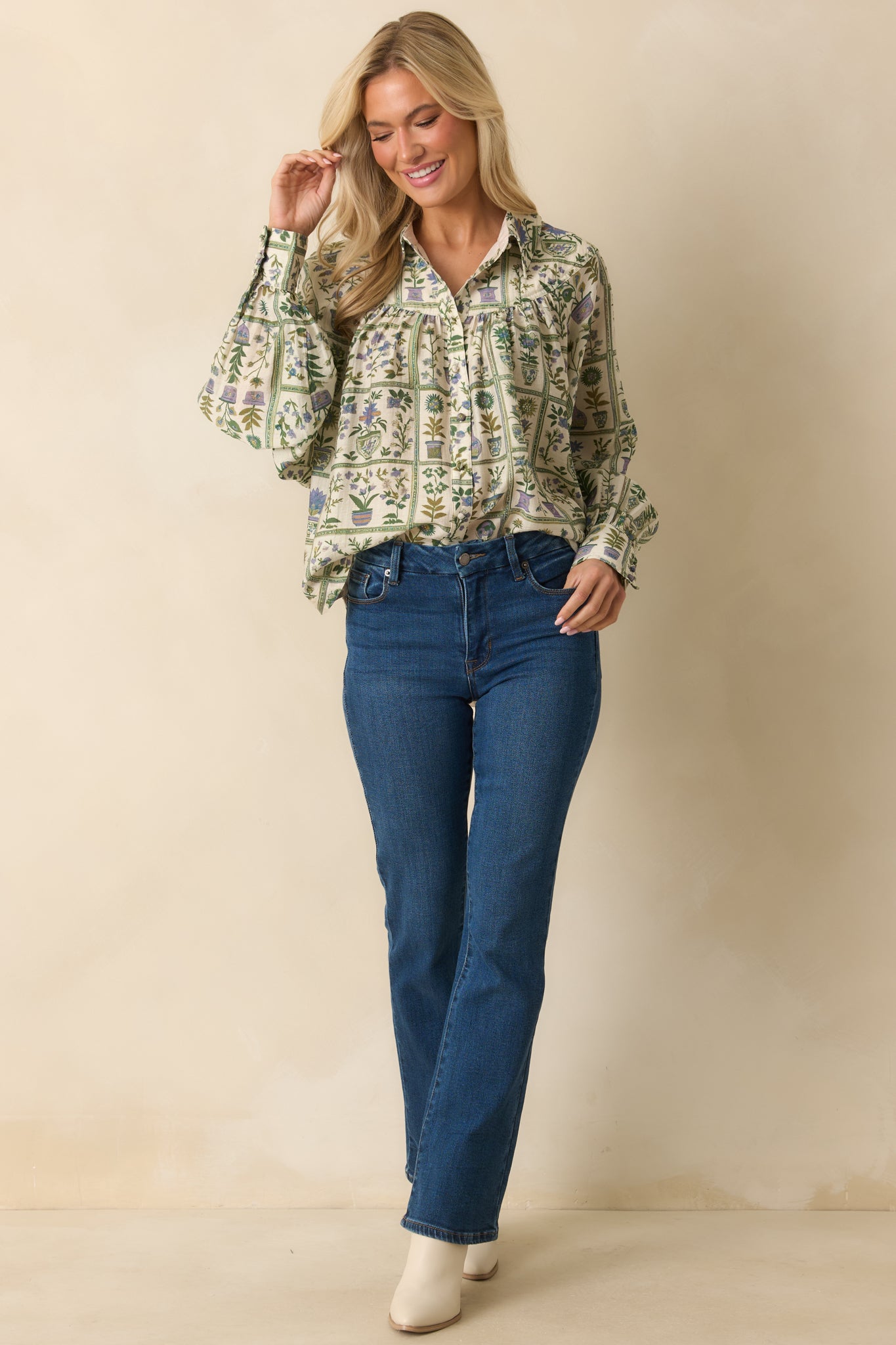 Green blouse with multicolor floral print, collared neckline, and relaxed fit featuring long sleeves with button cuffs.