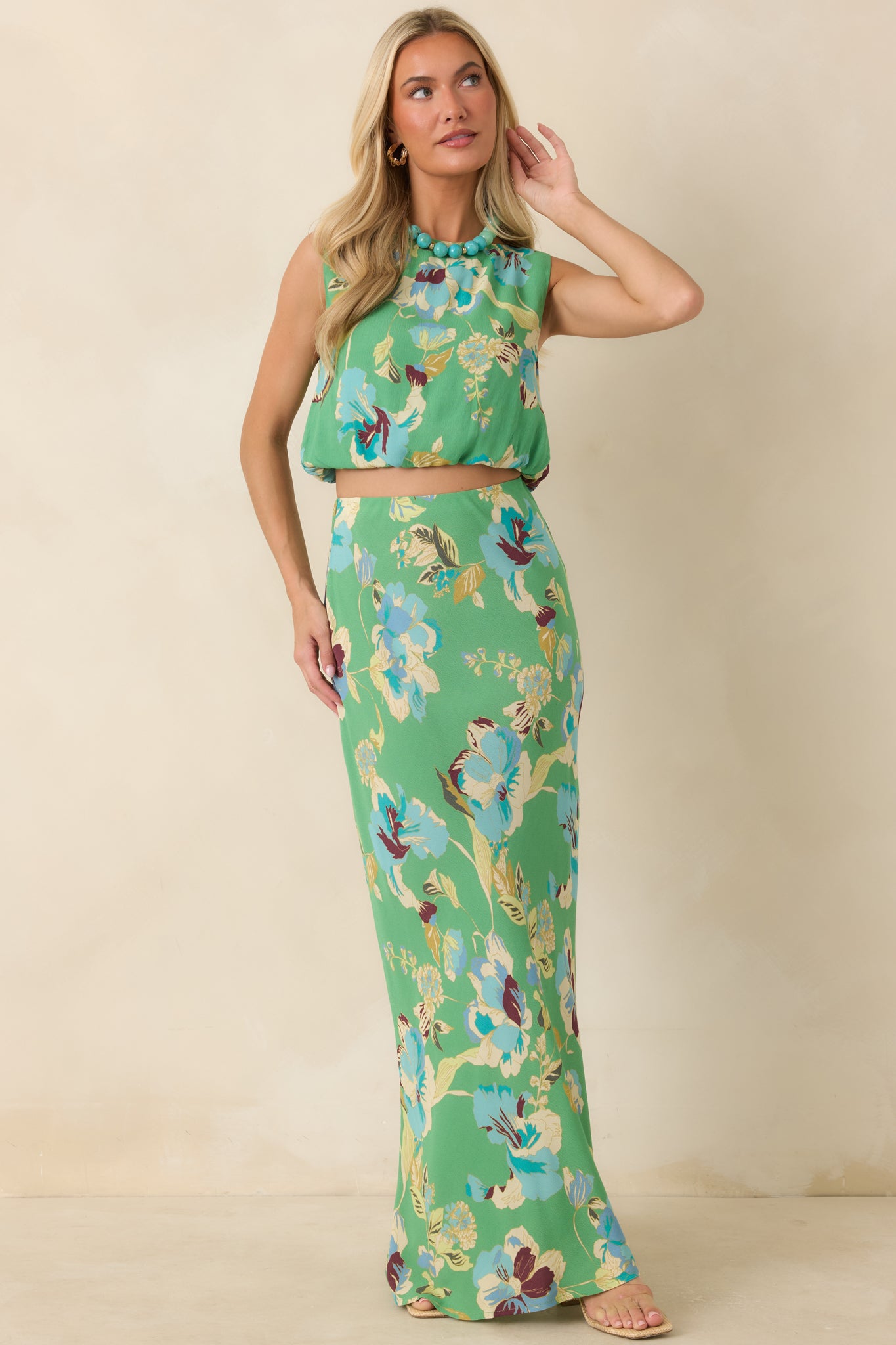 Green floral woven viscose top featuring a sleeveless silhouette, round neckline, and elastic bubble hem.
