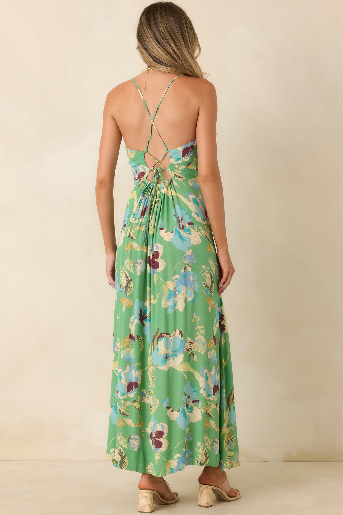 Back of the green floral maxi dress featuring an open back, crisscross straps, and adjustable tie detail.