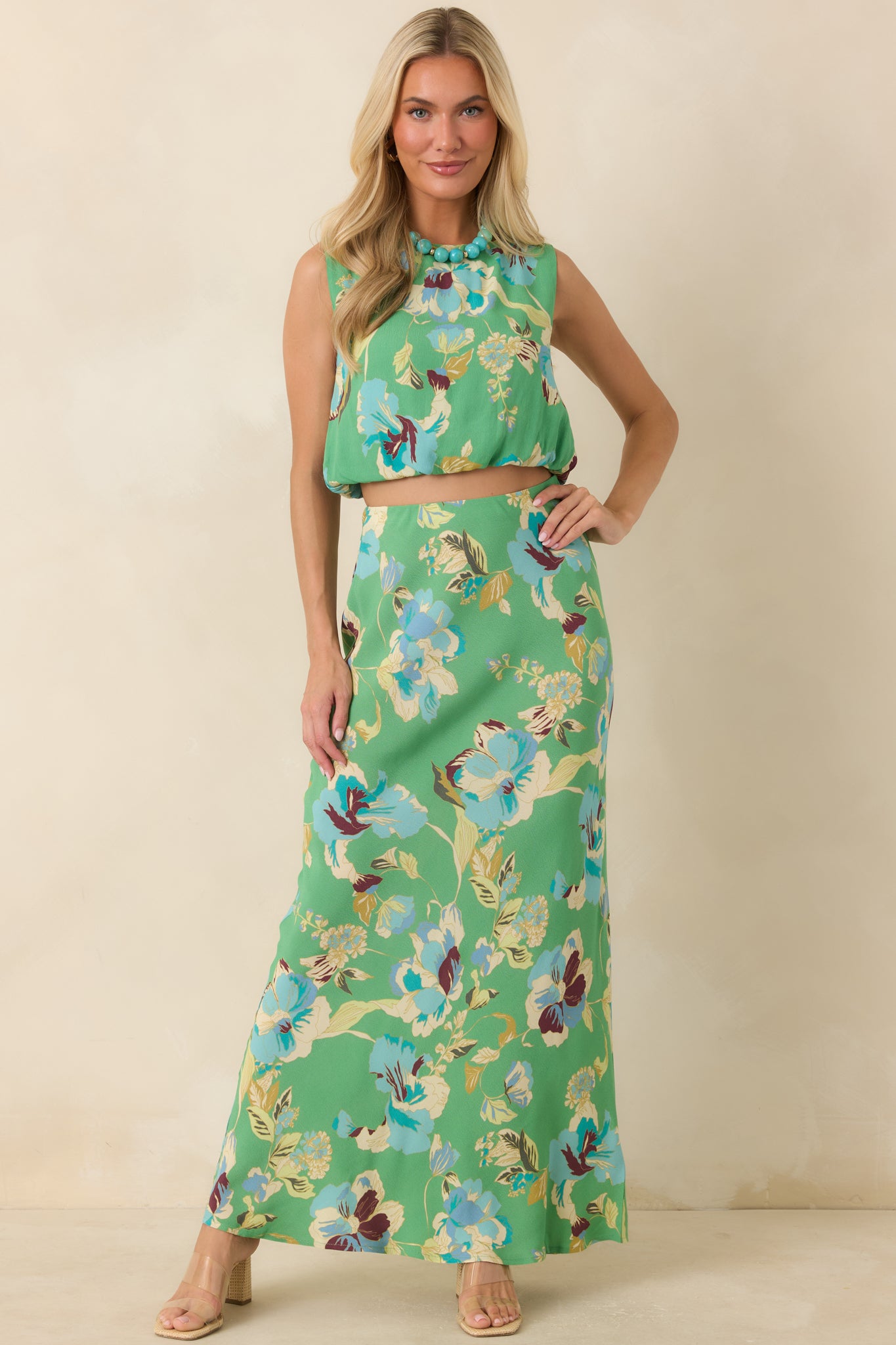 Vacation-ready maxi skirt with vibrant green fabric, bold blue florals, and a graceful fluid drape.