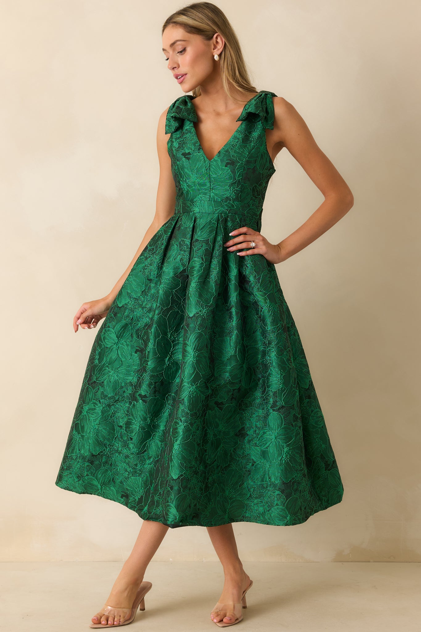Full-length front view of green floral midi dress featuring sleeveless design, V-neckline, self-tie bow straps, and functional side pockets