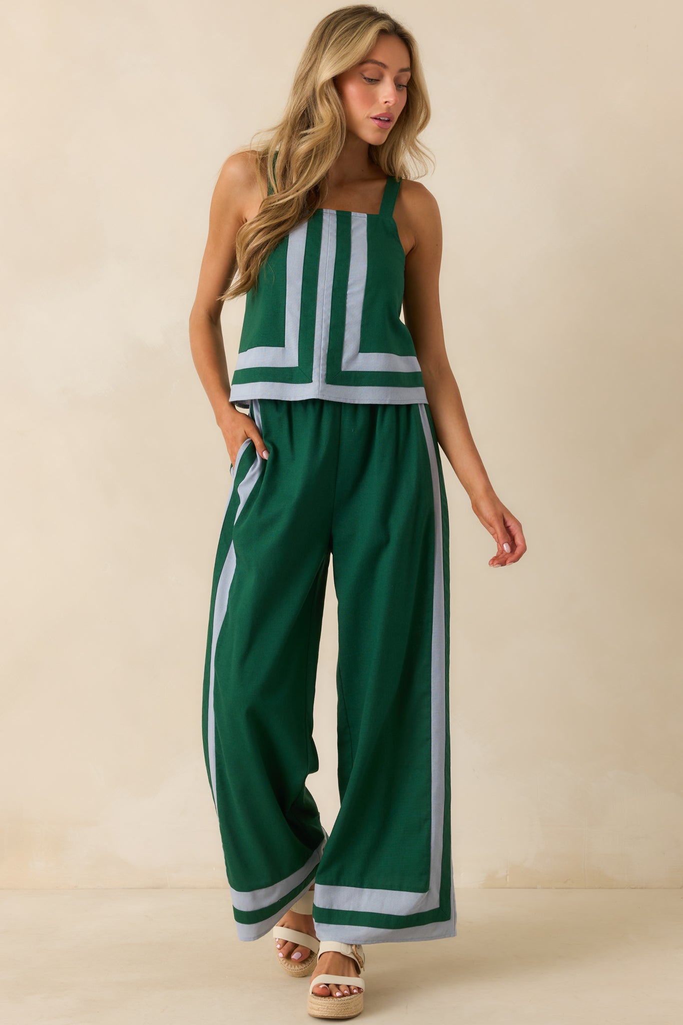 Green high-rise pants shown in full length highlighting the relaxed wide-leg fit and blue trim details.