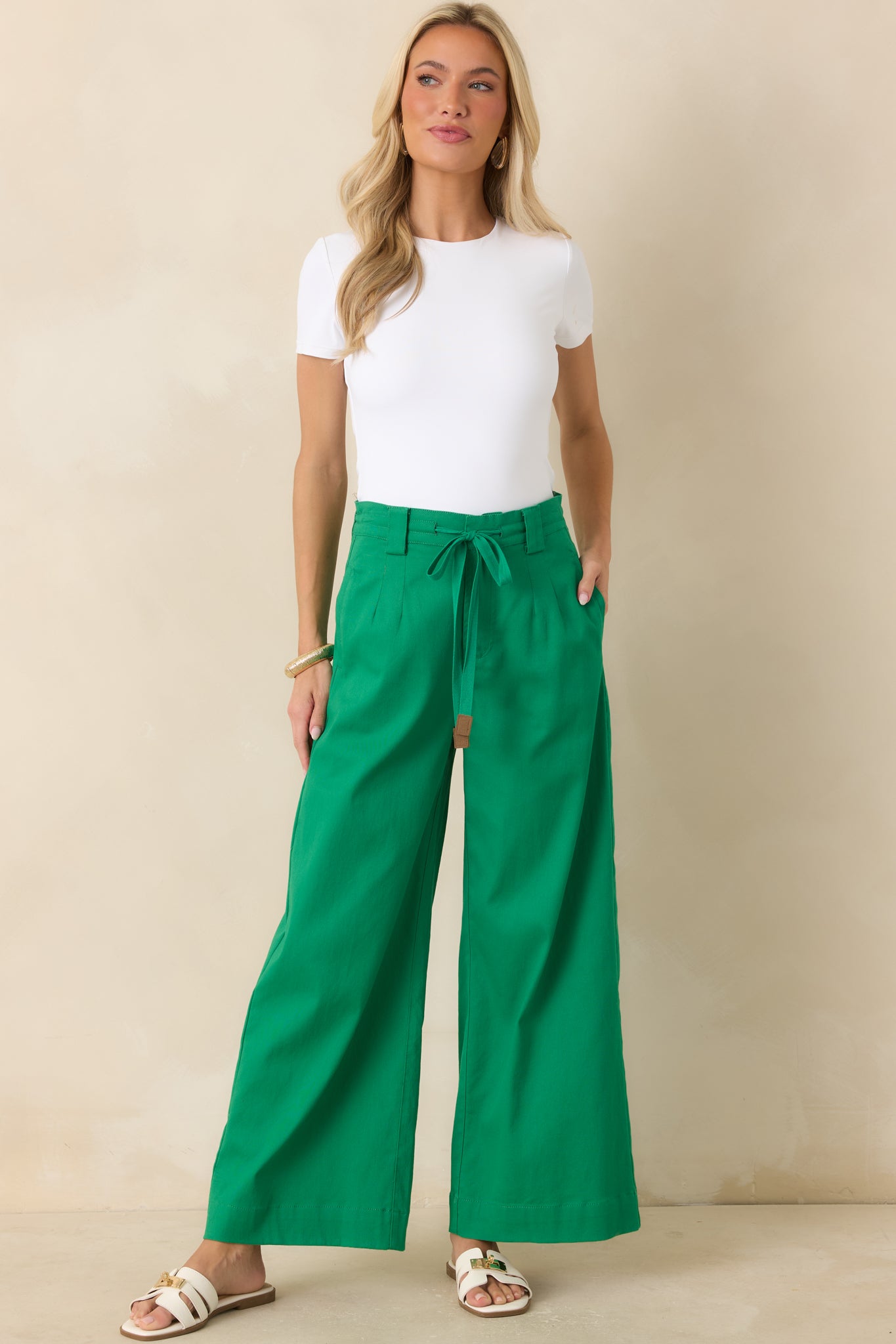 Green wide leg pants showcasing a structured waistband, relaxed fit, side pockets, and polished full-length drape.