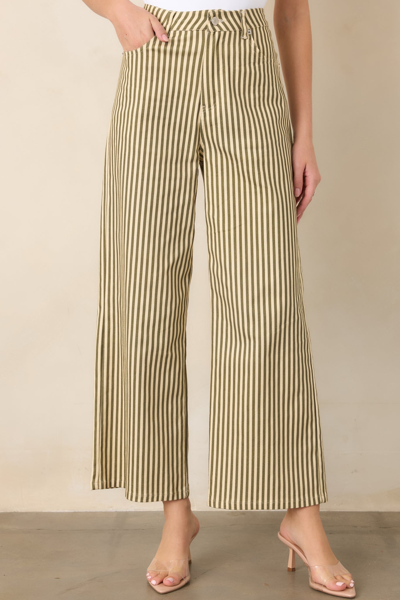 Close view of the green and ivory striped pants highlighting the waistband, belt loops, zip fly, and button closure.