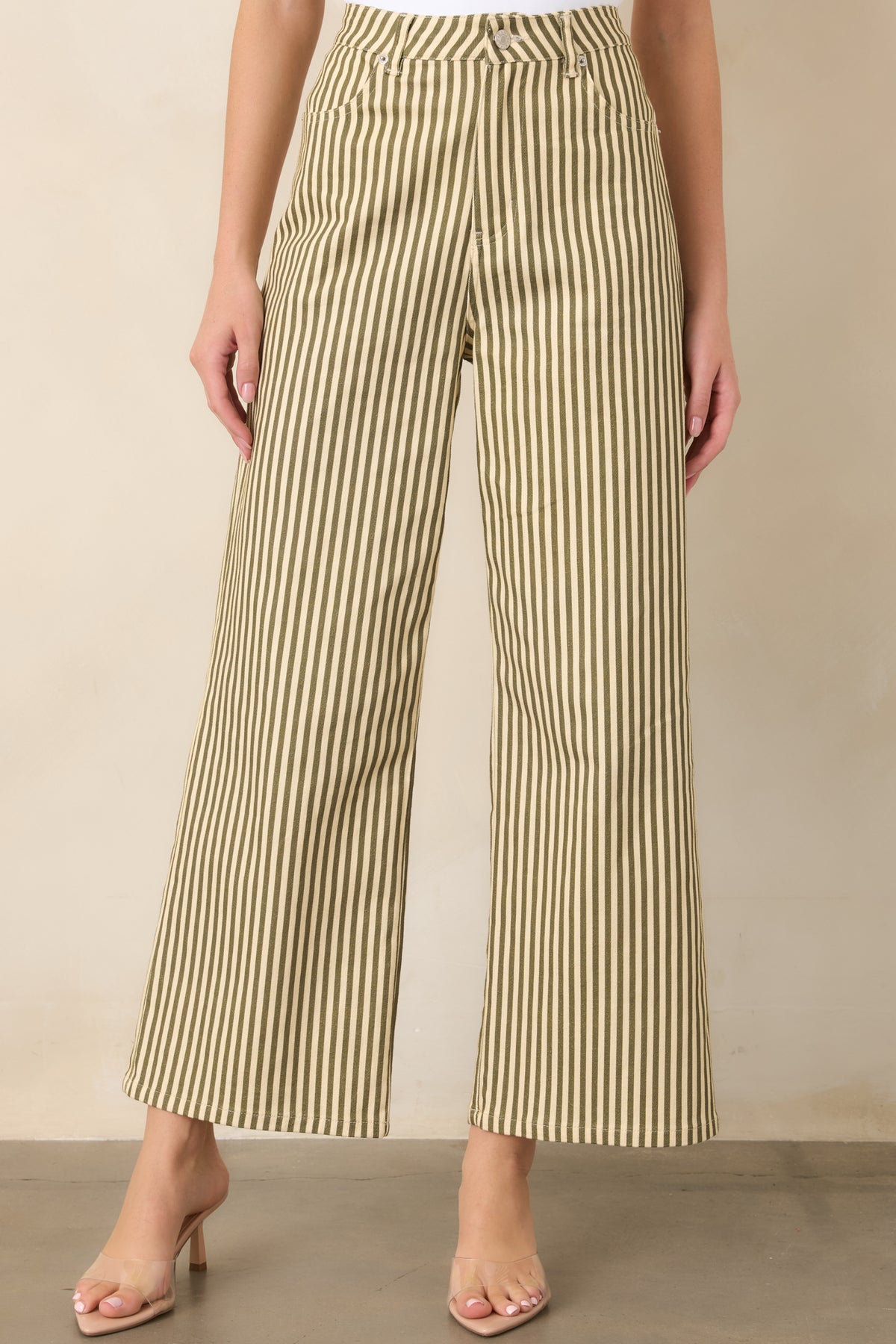 Close-up of the green and ivory striped pants highlighting the zip-and-button closure, belt loop, waistband, and neatly finished vertical stripes.