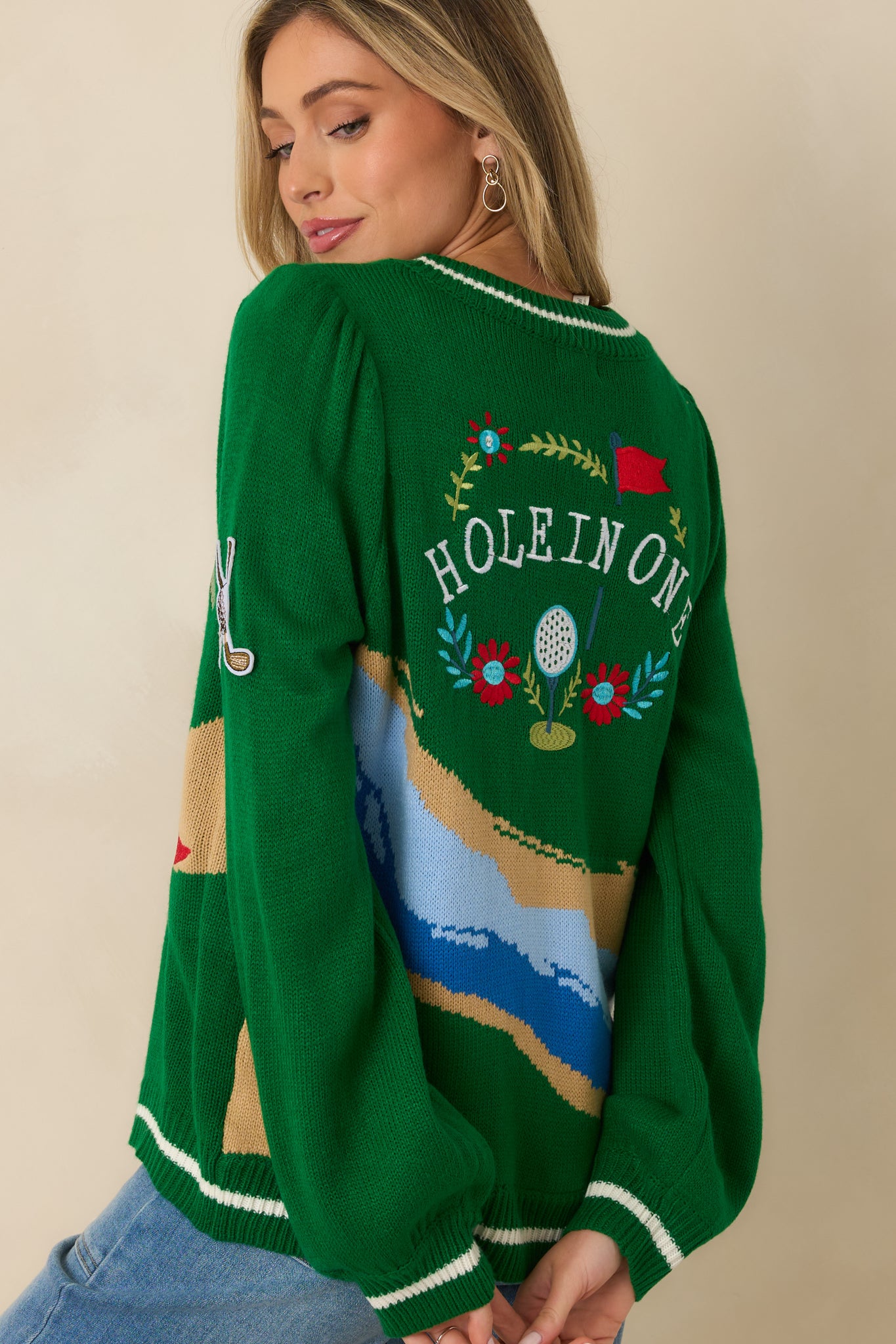 Back view of the green knit cardigan highlighting the ribbed hem, long sleeves, and uninterrupted knit-in graphic pattern.