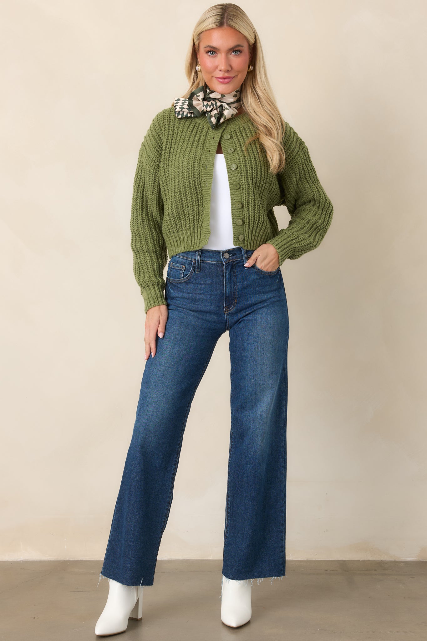 Green knit cardigan showcasing a full button front, ribbed trim, long sleeves, and a compact cropped silhouette.