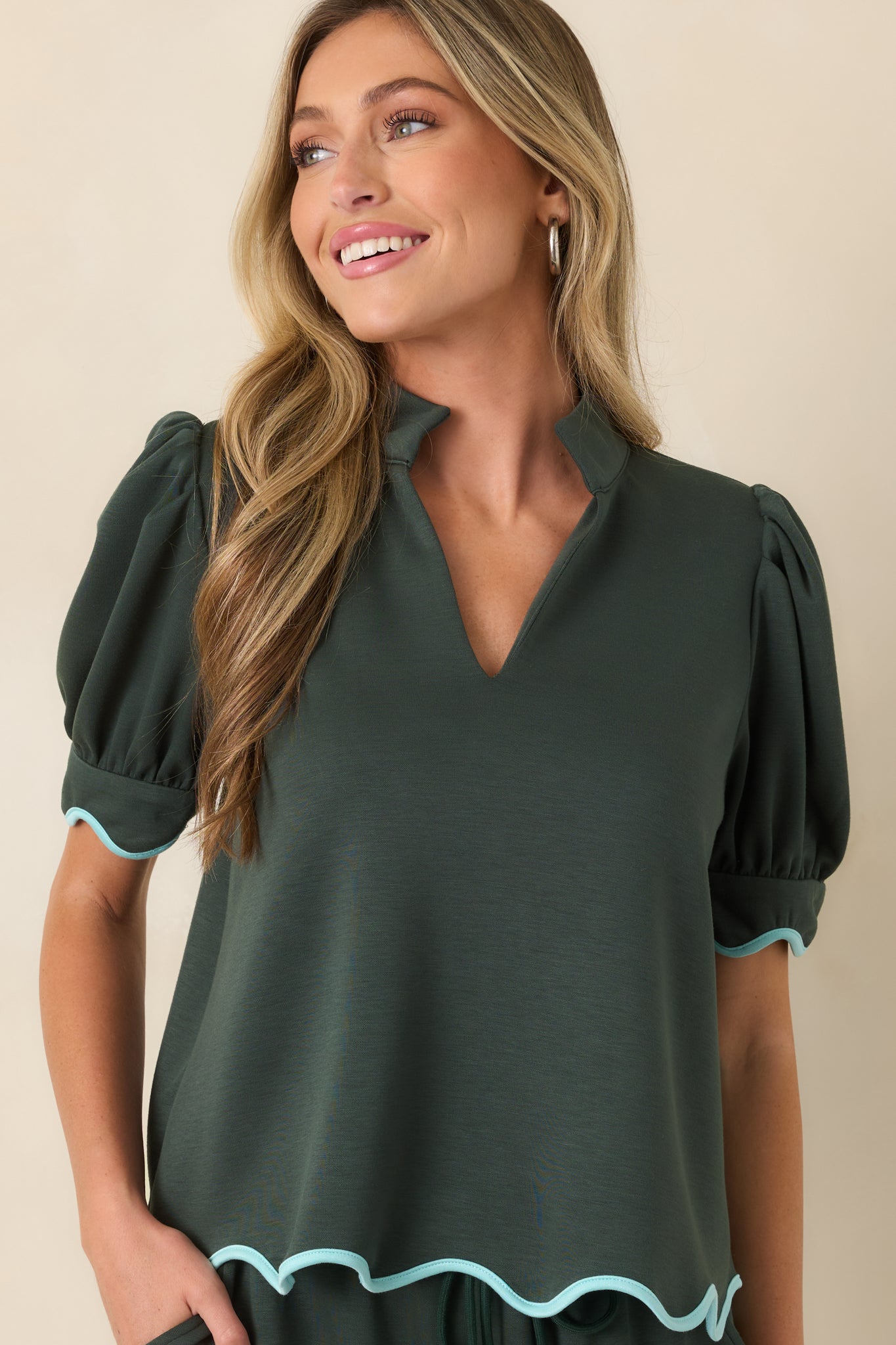 The front of this green knit top highlights the split neckline and structured stand collar.