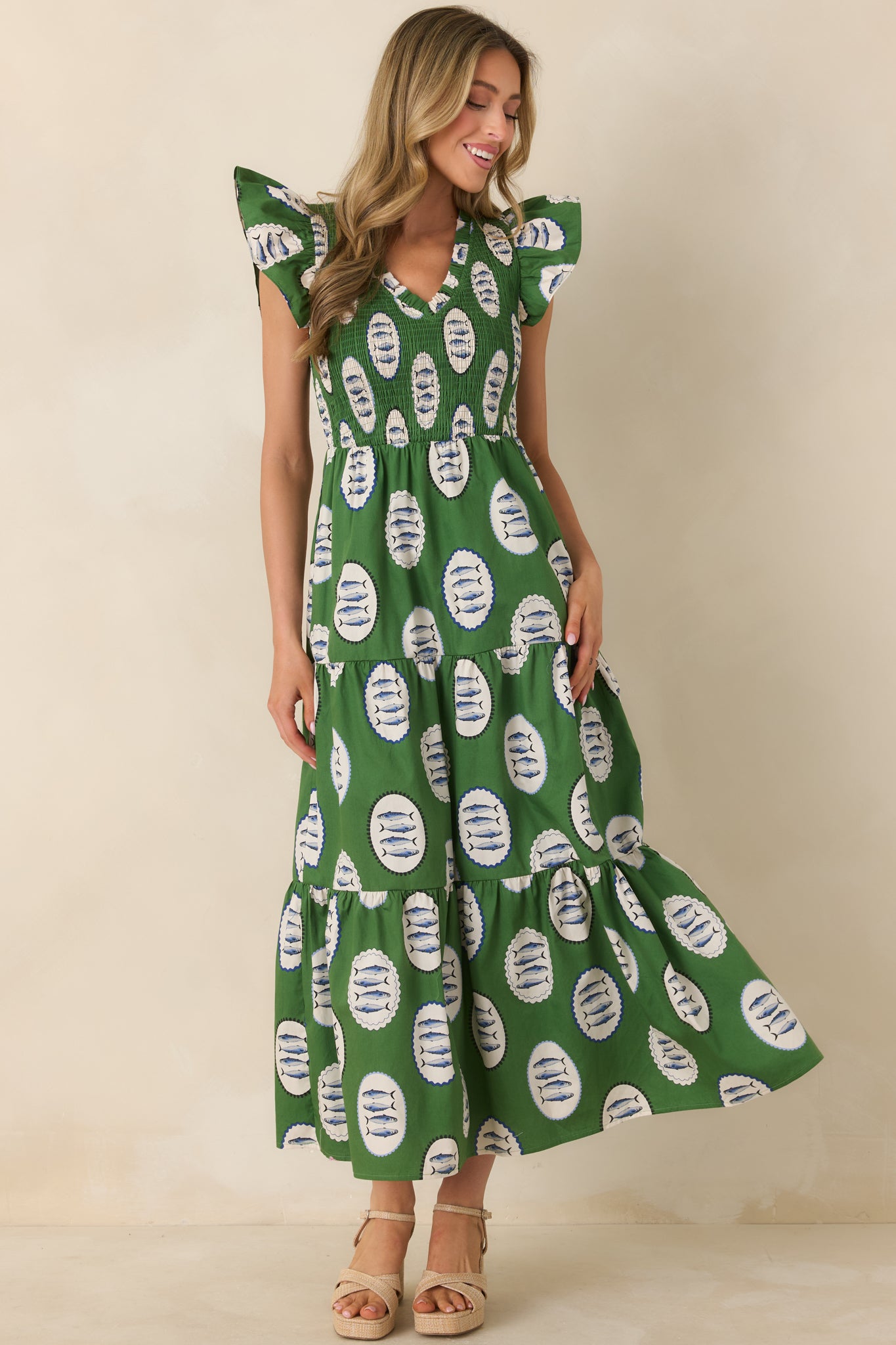 Green maxi dress with fish medallion print, smocked bodice, V-neckline, and tiered skirt