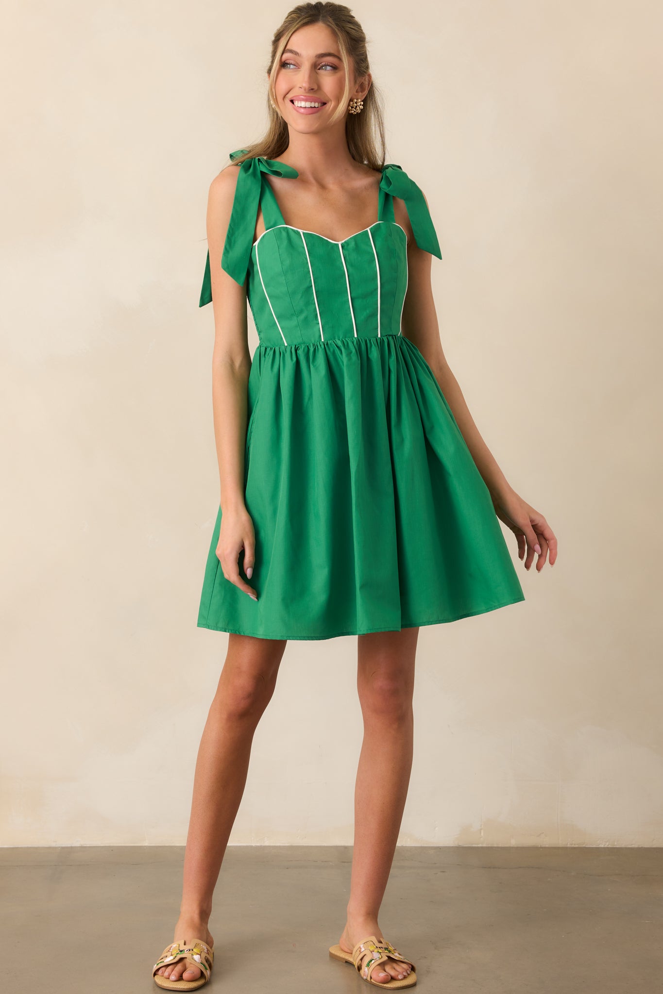 Front view of green mini dress highlighting structured bodice with white detailing and functional side pockets.