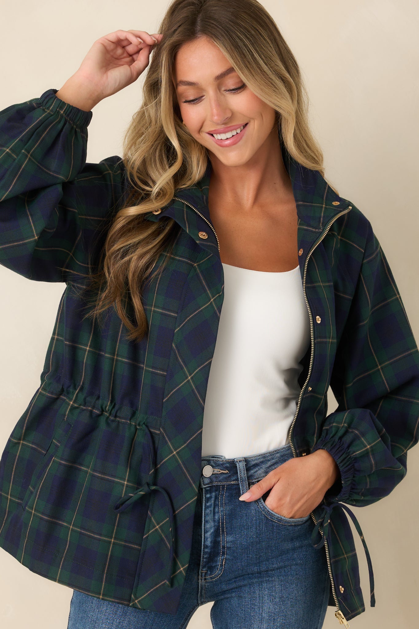 Close view of the jacket highlighting the structured collar, zip-front closure, snap accents, and rich green and navy plaid pattern.