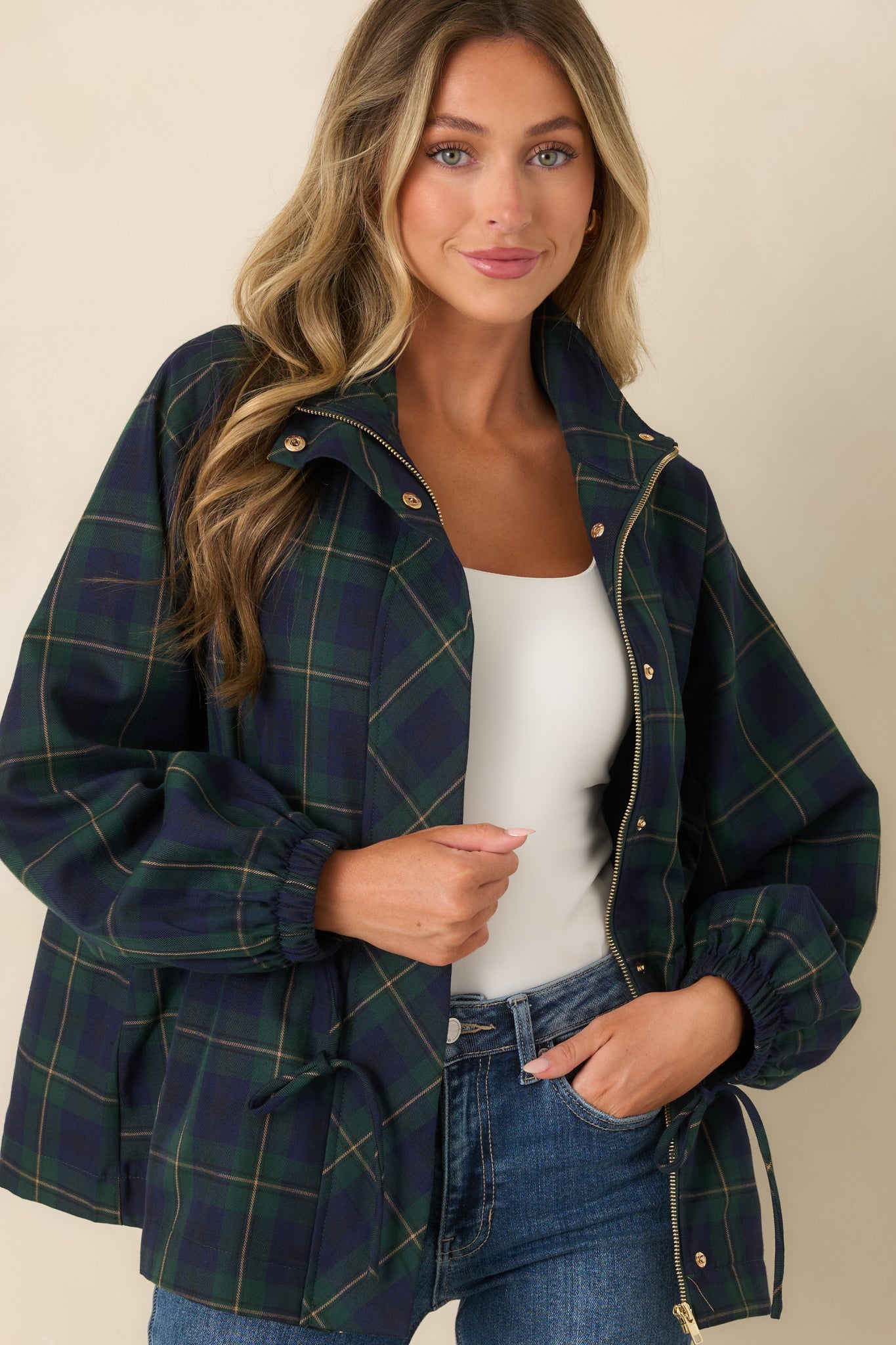 Cropped view of the jacket featuring the elastic cuffs, snap detailing, adjustable drawstring waist, and lightweight plaid fabric.