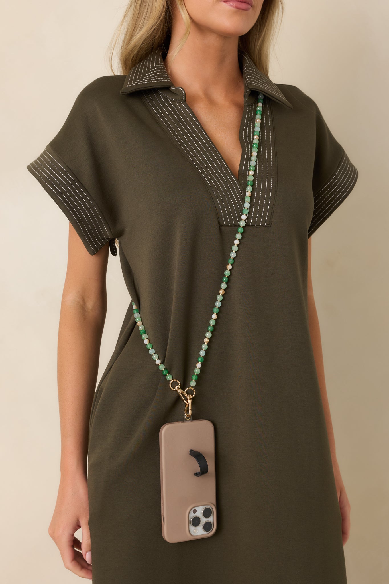 Jewelry-inspired phone lanyard with layered green beads and polished gold-tone accents creating an elevated accessory look