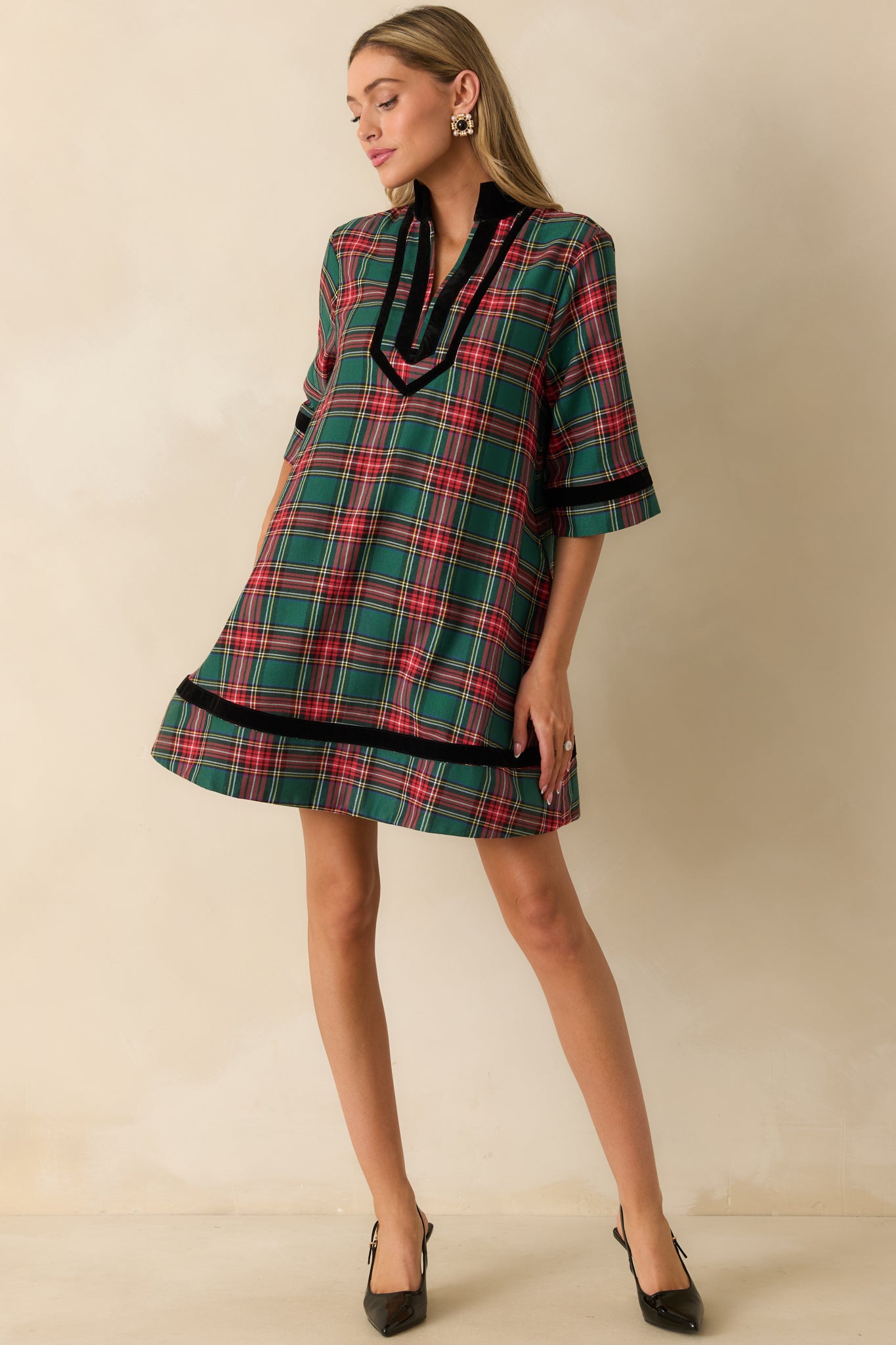 A-line green plaid mini dress highlighting elbow-length sleeves, split neckline, and subtle pocket details.