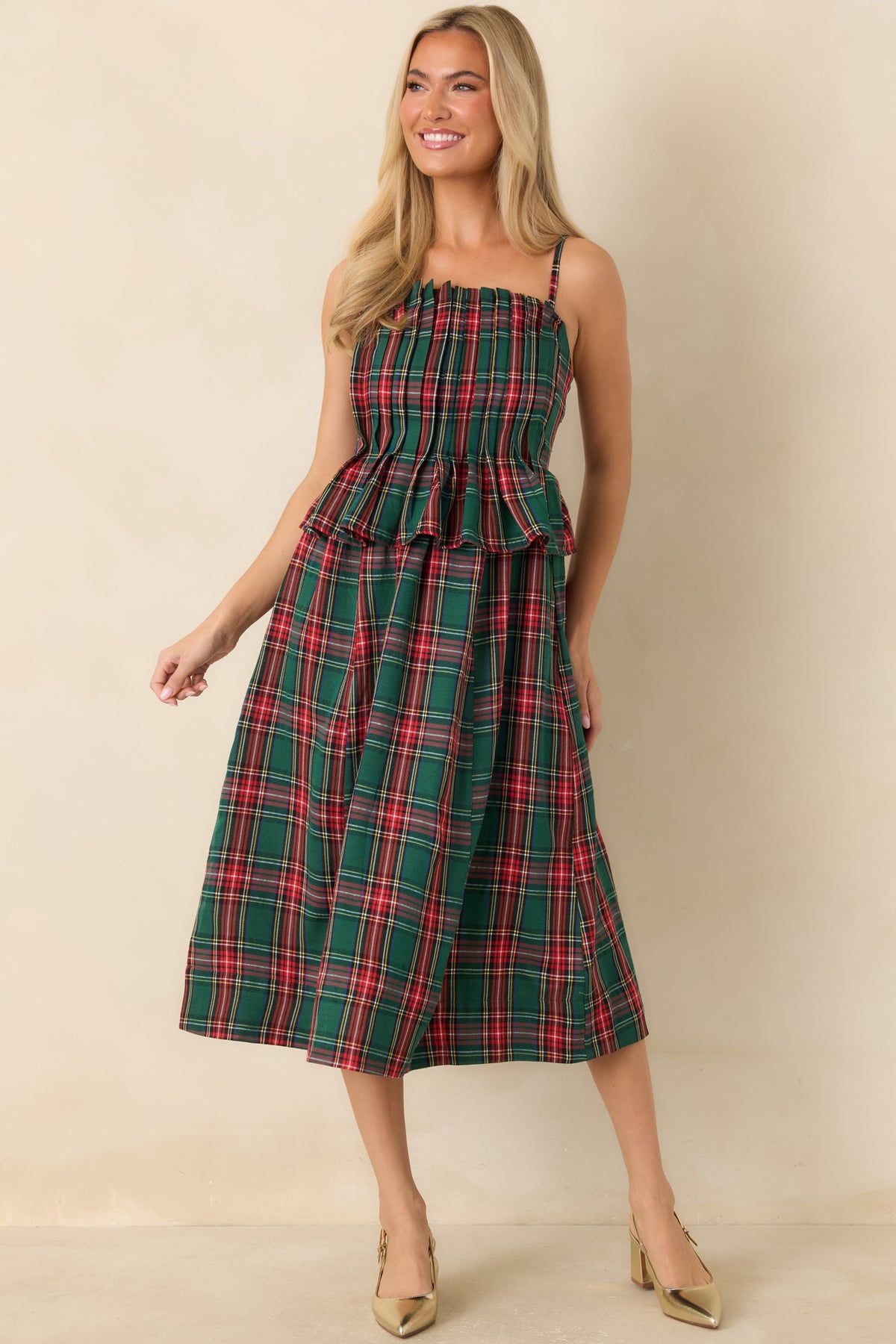 Green plaid midi dress showcasing a softly ruffled neckline and peplum flounce at the waist.