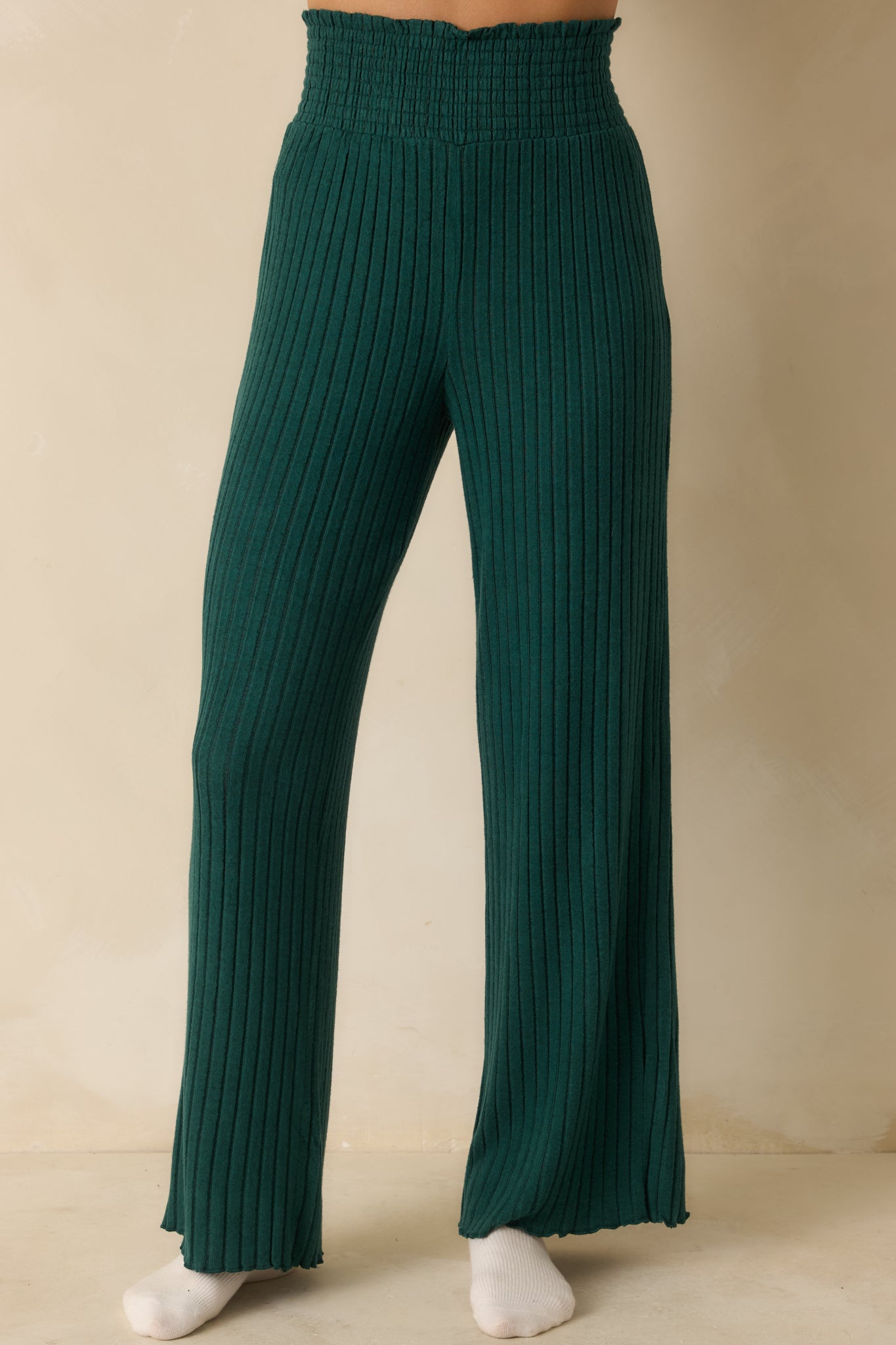 Green ribbed pants cropped mid-leg, highlighting fit-and-flare silhouette and silky knit texture.