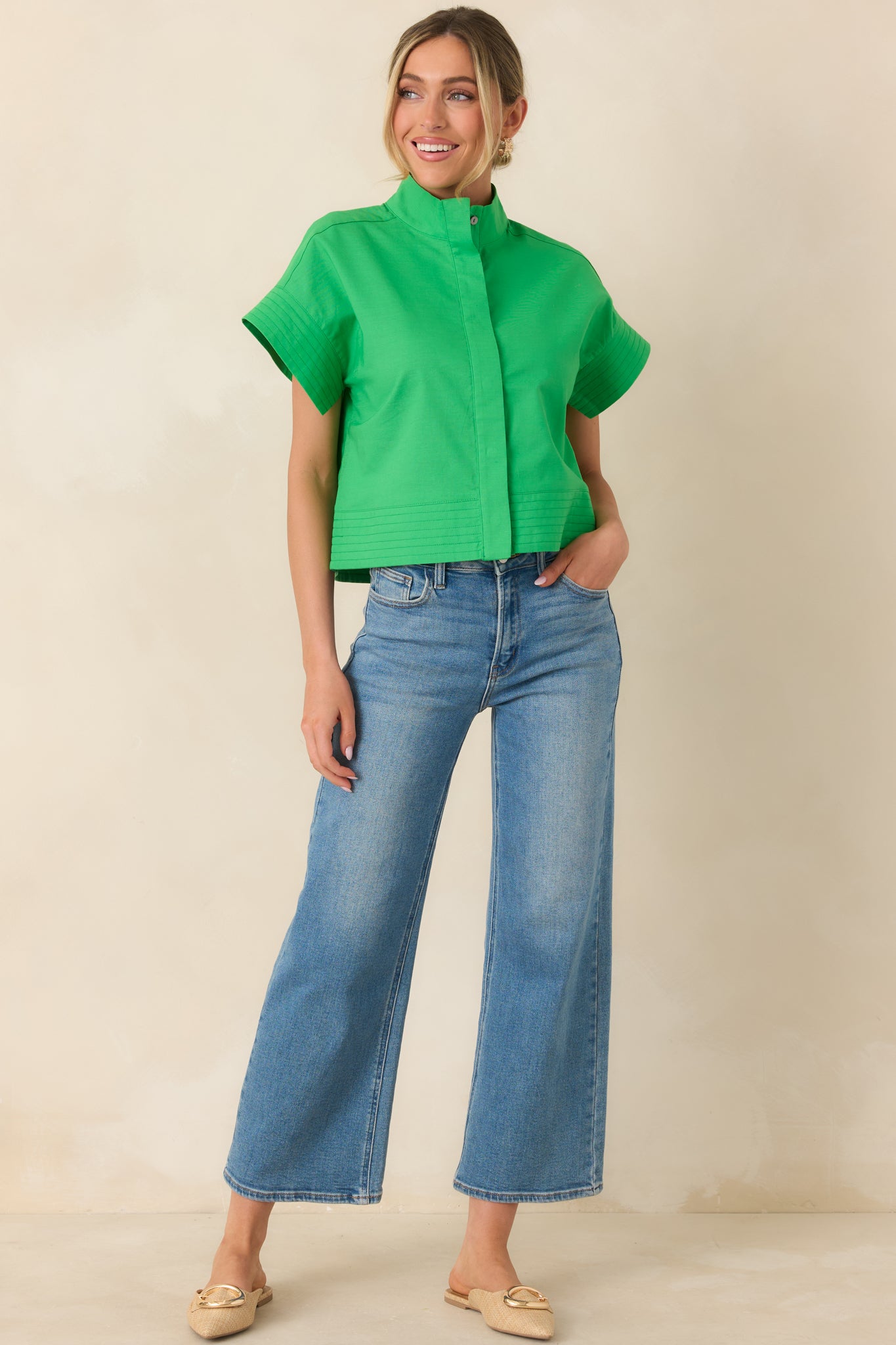 Structured green top featuring a straight hem, concealed button-front placket, and wide short sleeves.