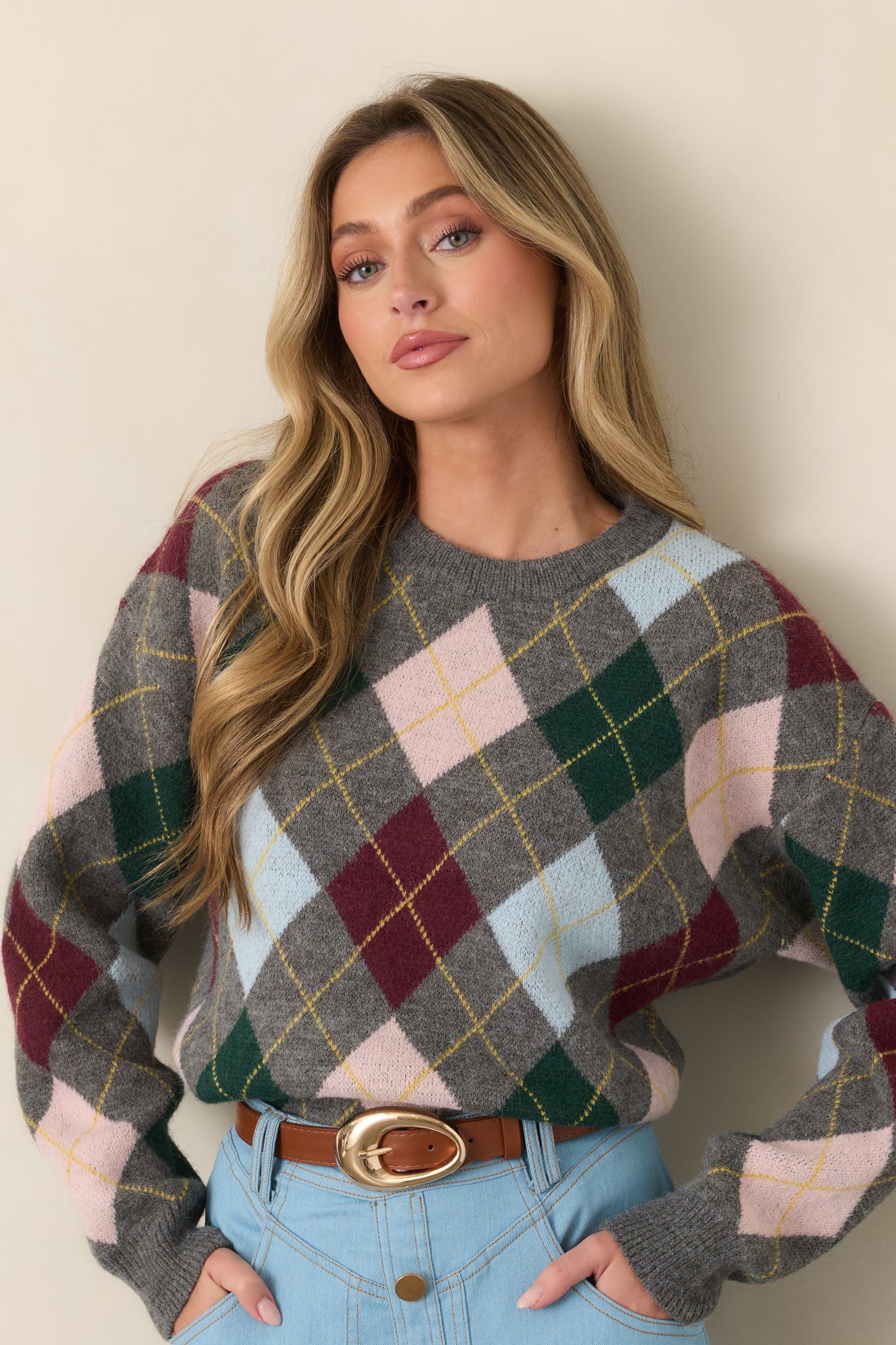 Close view of the grey argyle sweater highlighting the ribbed hem and colorful diamond motifs in burgundy, forest green, blush pink, light blue, and golden yellow.