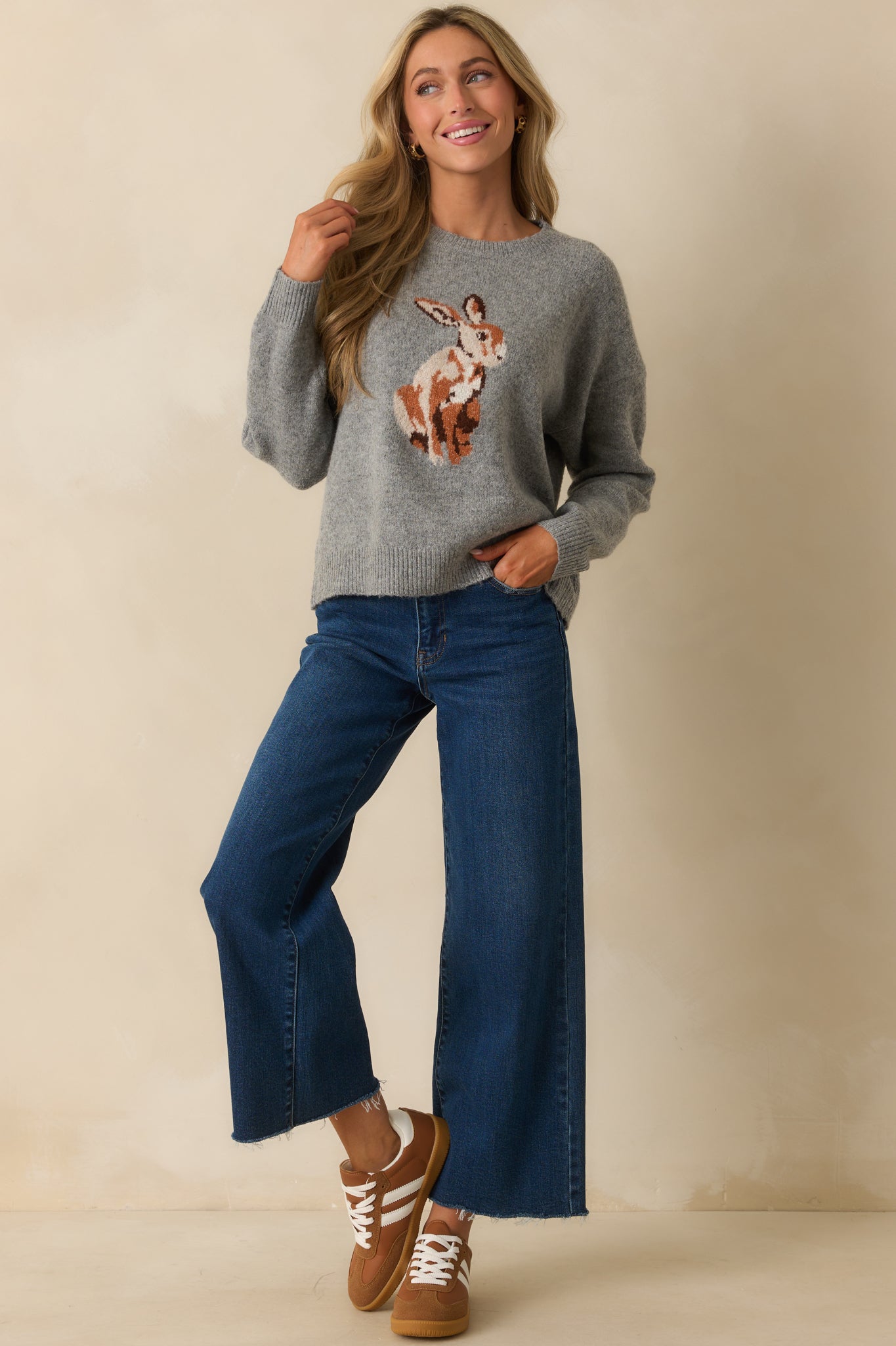 Grey sweater with crew neckline and long sleeves featuring ribbed cuffs.