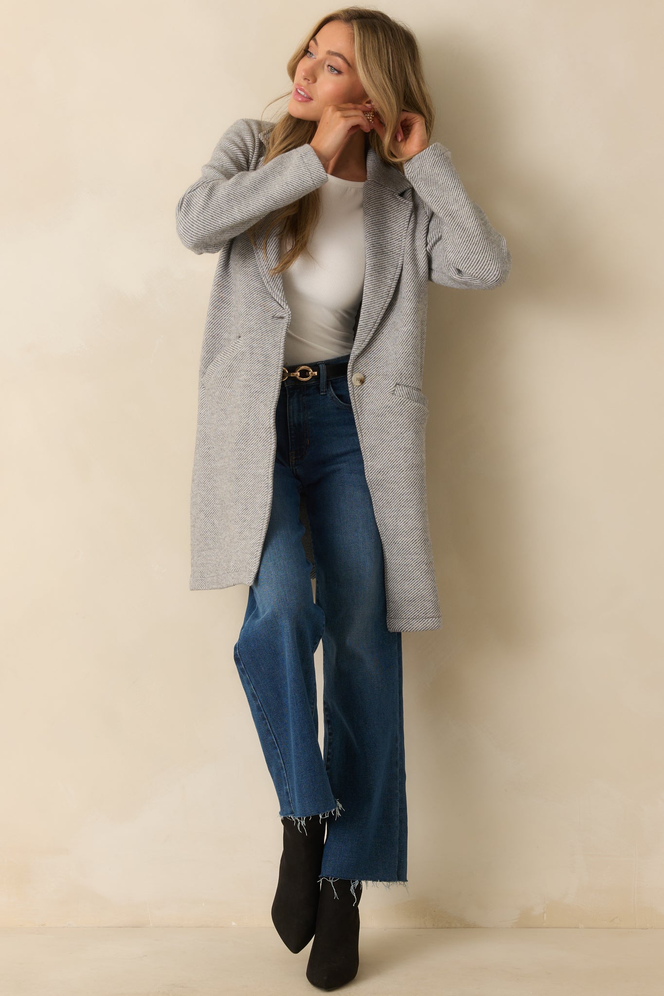 Longline grey coat featuring a button-front closure, structured lapels, and welt pockets.