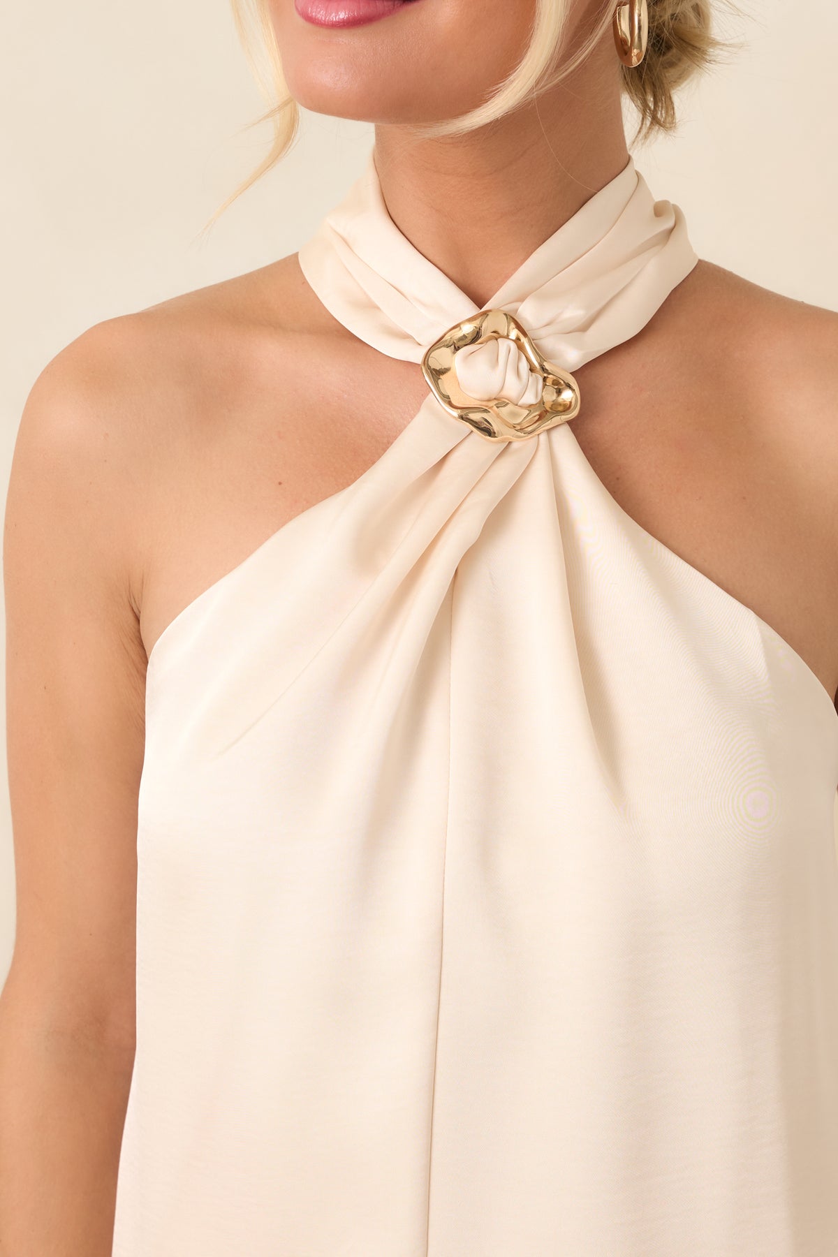 Close-up of the decorative ring accent at the halter neckline surrounded by gathered fabric.