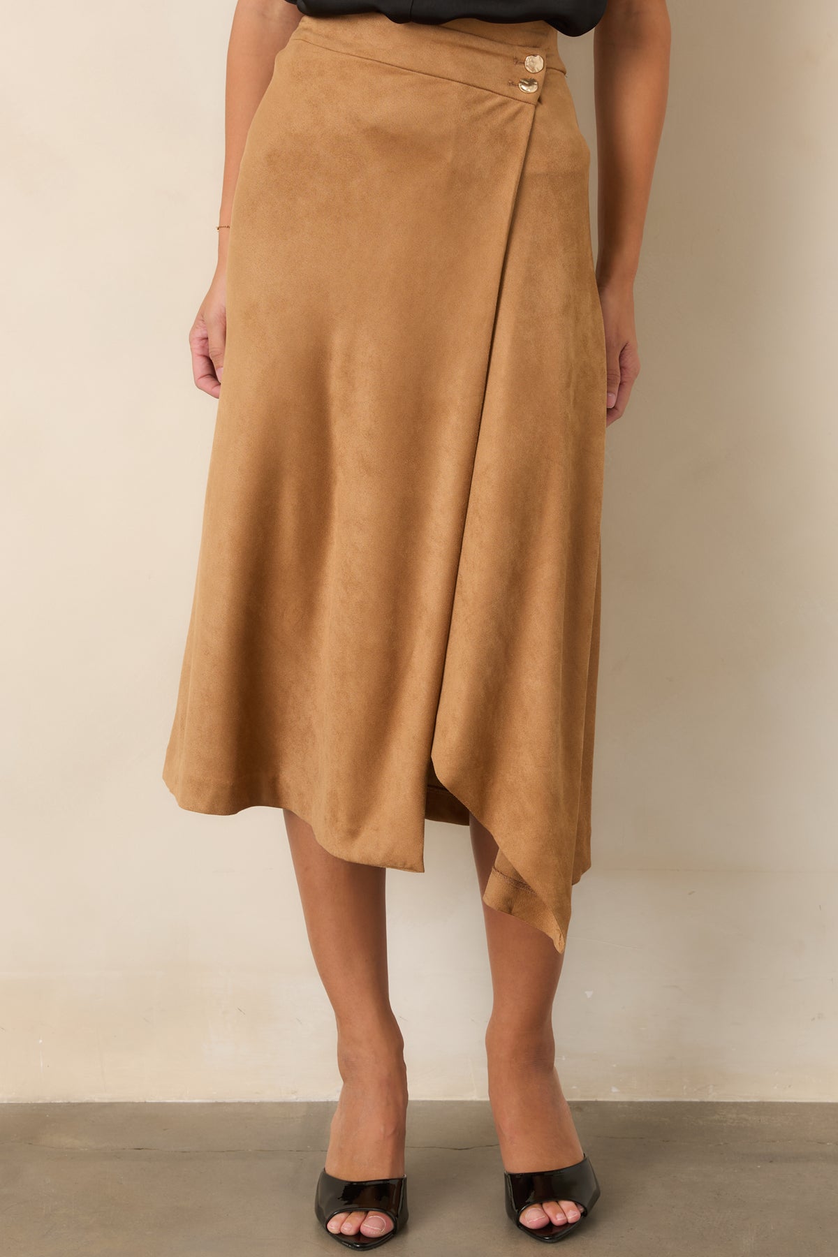 Hammered gold-tone buttons accent the asymmetrical wrap front of this streamlined faux suede skirt.