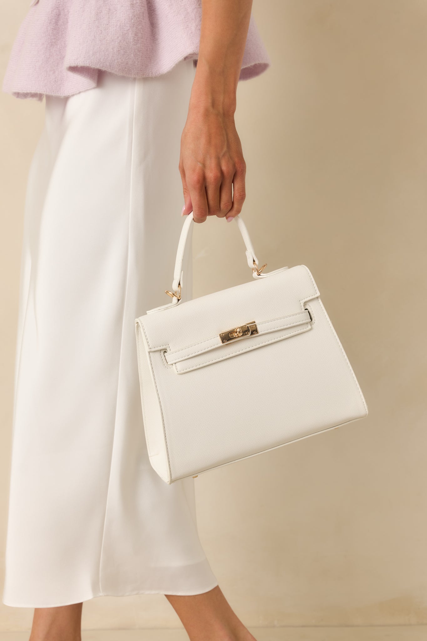 Alternate full front view of handbag showing structured silhouette and overlapping strap design with twist lock closure.