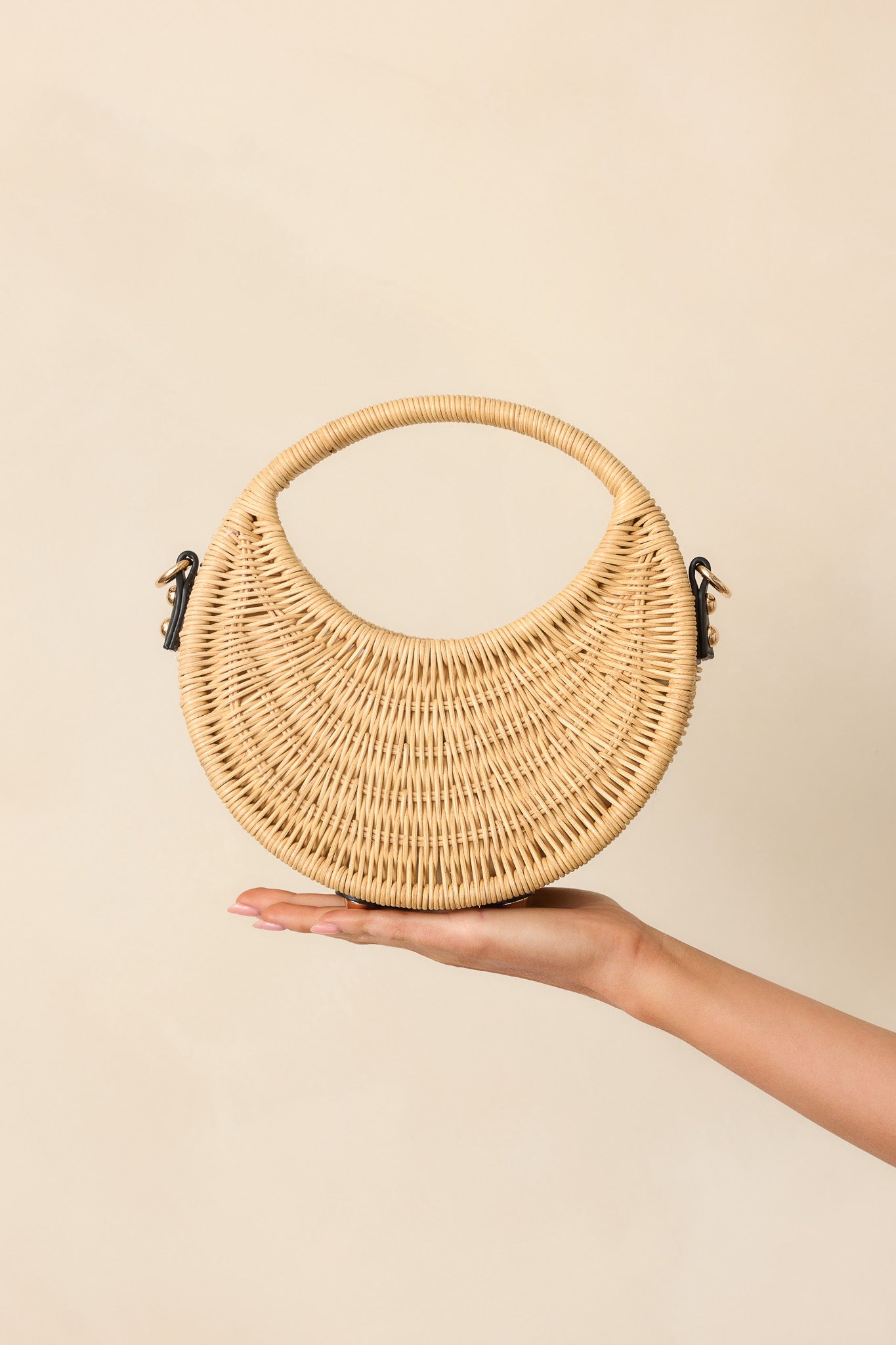 Zoomed-in view of the upper portion of the handbag, featuring the rattan handle, gold hardware, and black faux leather trim.