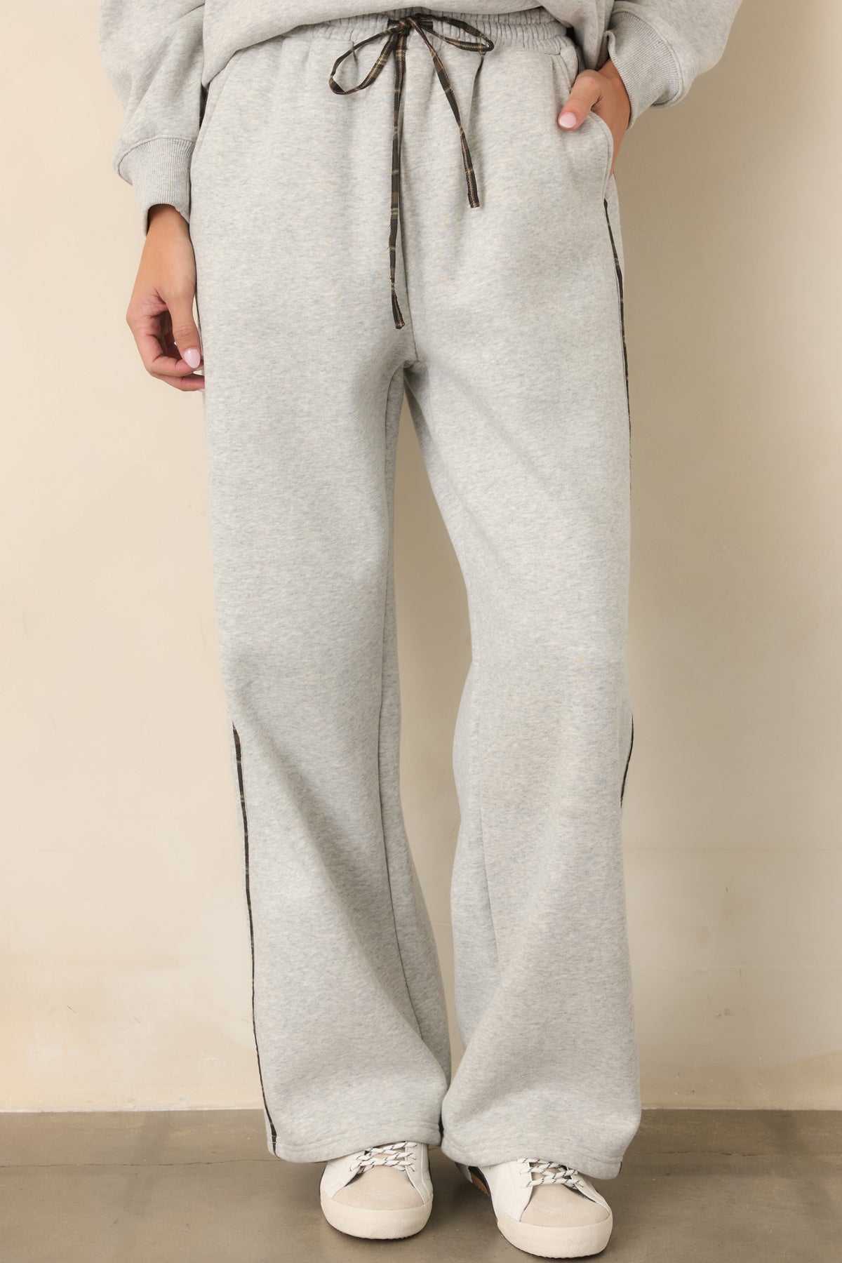 Heather grey sweatpants showcasing the comfortable waistband, drawstring closure, and plaid stripe detail.
