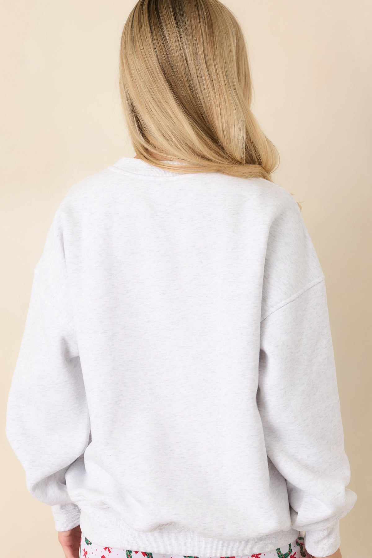 Back of the heather grey pullover featuring a plain fabric design with long sleeves and ribbed crewneck, cuffs, and hem.