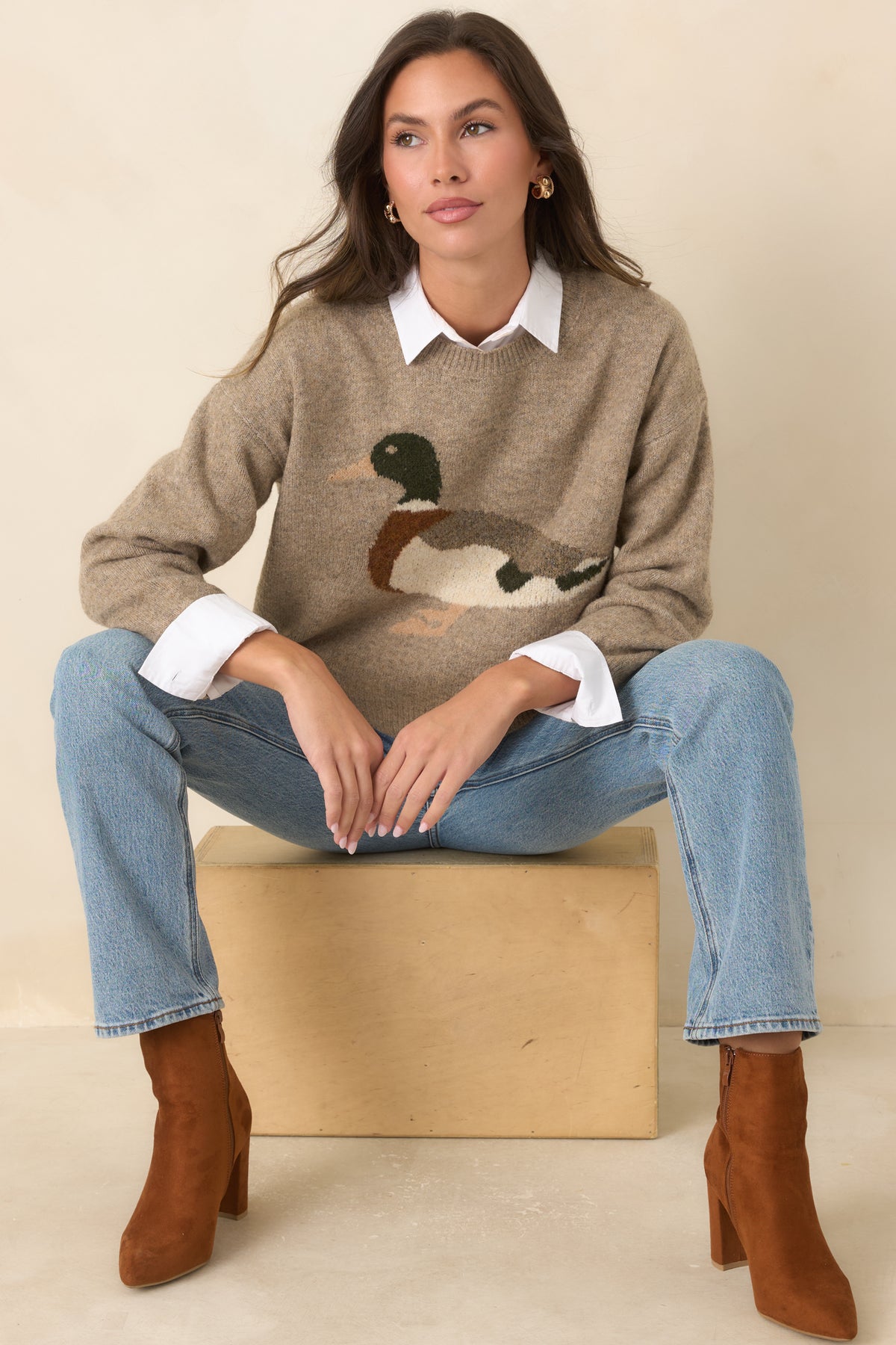 Heathered taupe sweater features a colorful mallard motif, relaxed boxy fit, dropped shoulders, and ribbed trim.