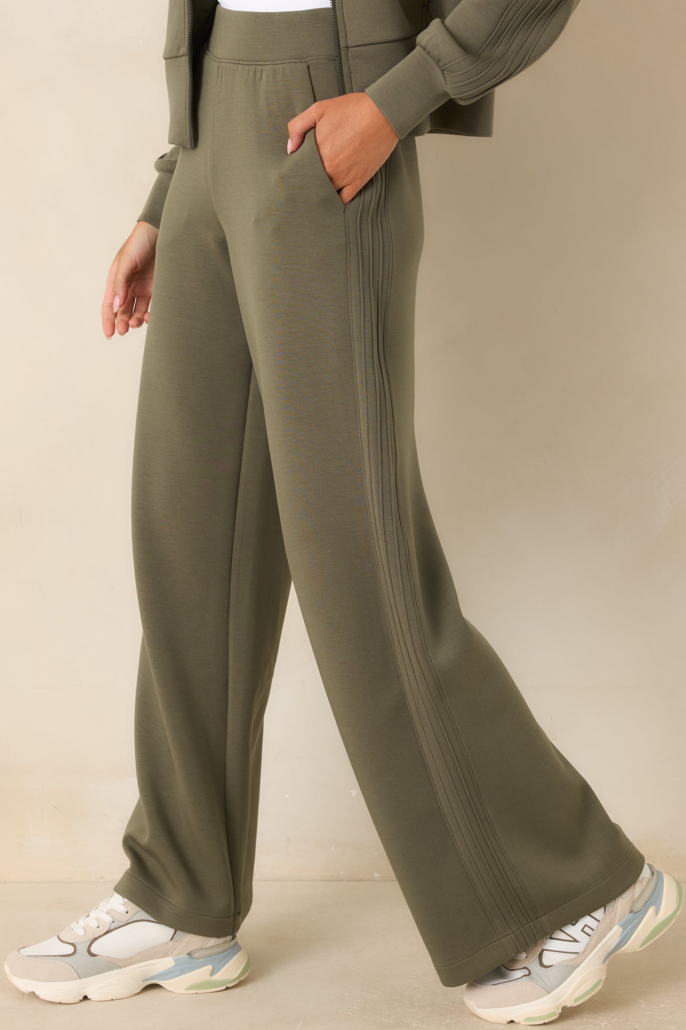 Herb green pants showcasing the fluid wide-leg shape, side pocket placement, and streamlined seam detailing.