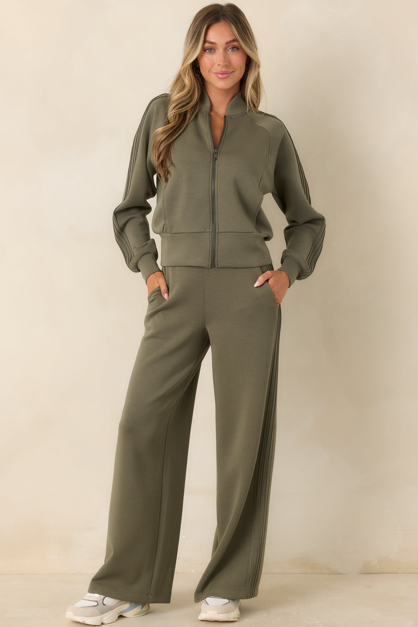 Herb green stretch pants featuring a high-rise pull-on waistband, fluid wide legs, raised pintuck seams, and side pockets.