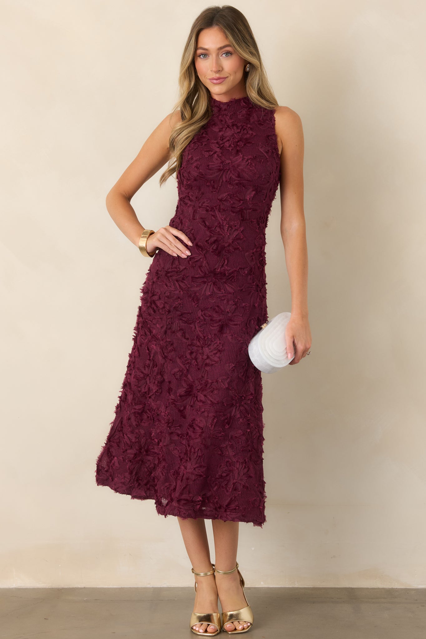 Fitted floral knit midi dress highlighting its high neckline, sculpted bodice, textured appliqué detailing, and softly flared silhouette.