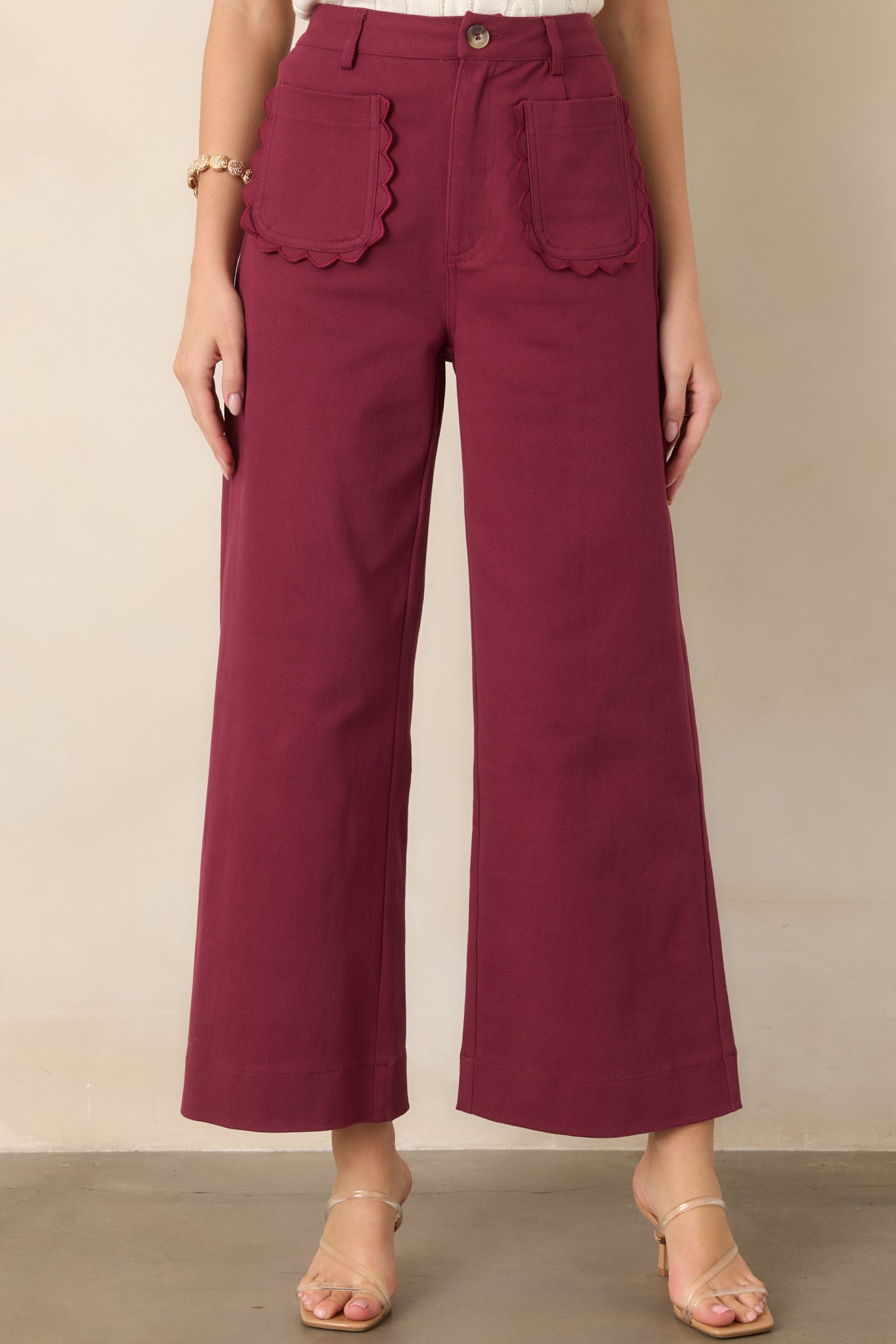 Close view of the high-rise waistband highlighting the button and zipper closure, belt loops, and scalloped front patch pockets.