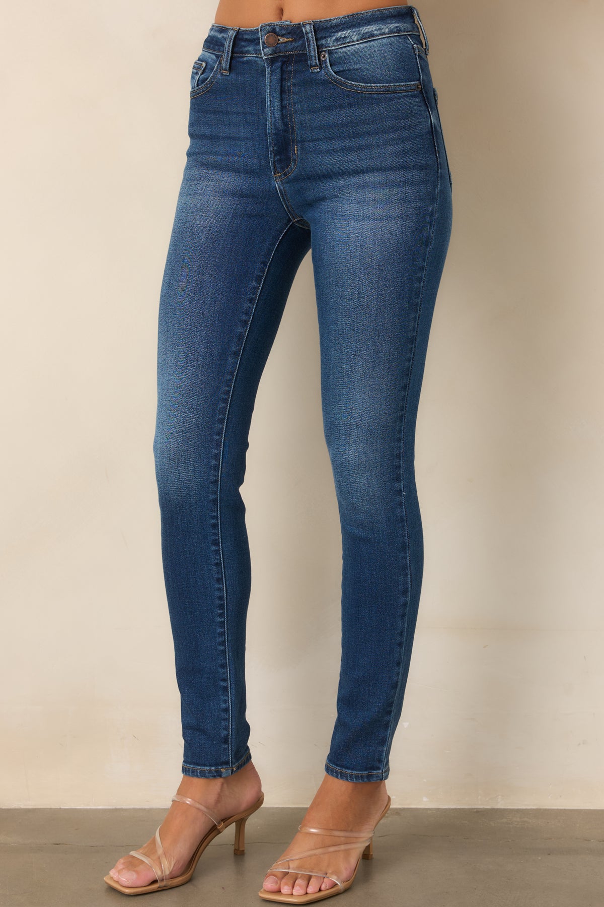 High-rise dark wash jeans showcasing the classic five-pocket styling and slim fit.